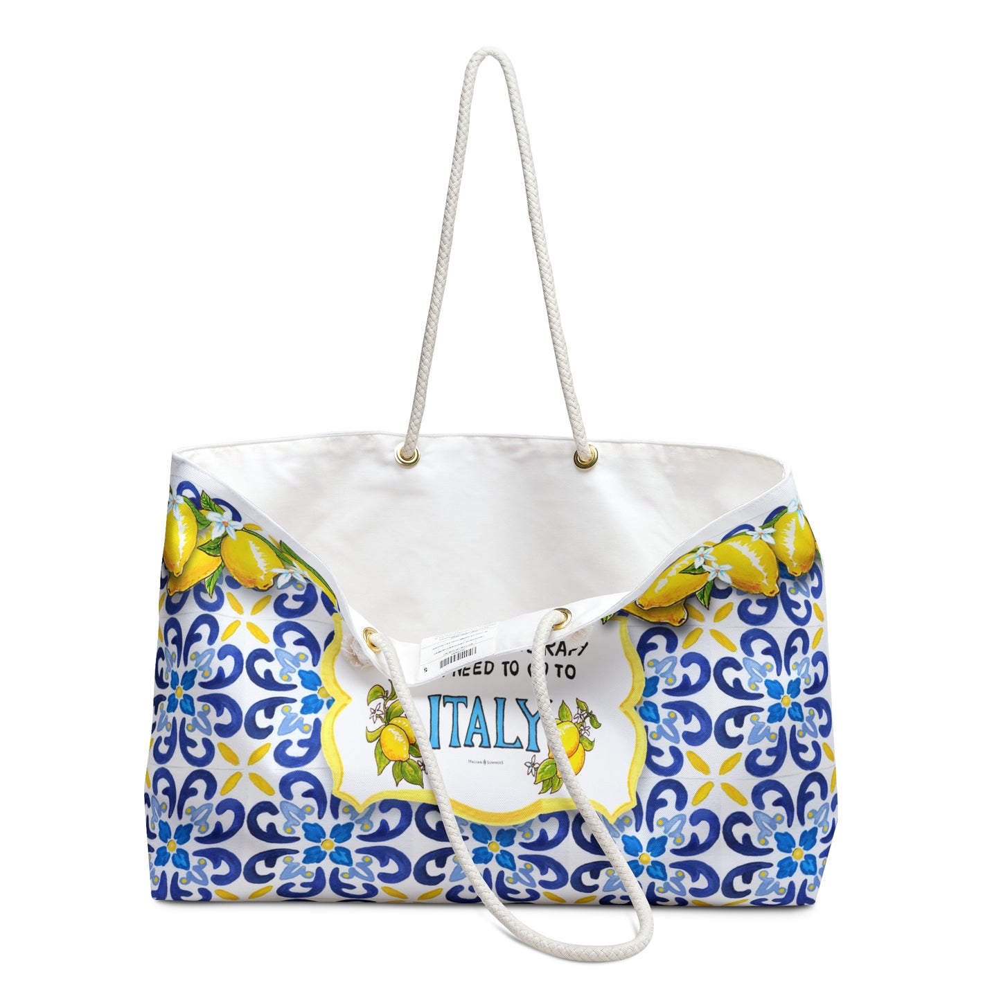 Italy inspired beach bag large model. It has the quote I don't need therapy, I just need to go to Italy. Next to the Italy writing a big Amalfi Coast lemons. The whole bag is printed with Italian tiles, colors blue with some yellow. On the rim of the bag there is a garland of lemons with lemon flowers. The quote with theblemons is placed on a white crest, and the crest is placed in the tile background. The Italy beach bag has soft rope handles.