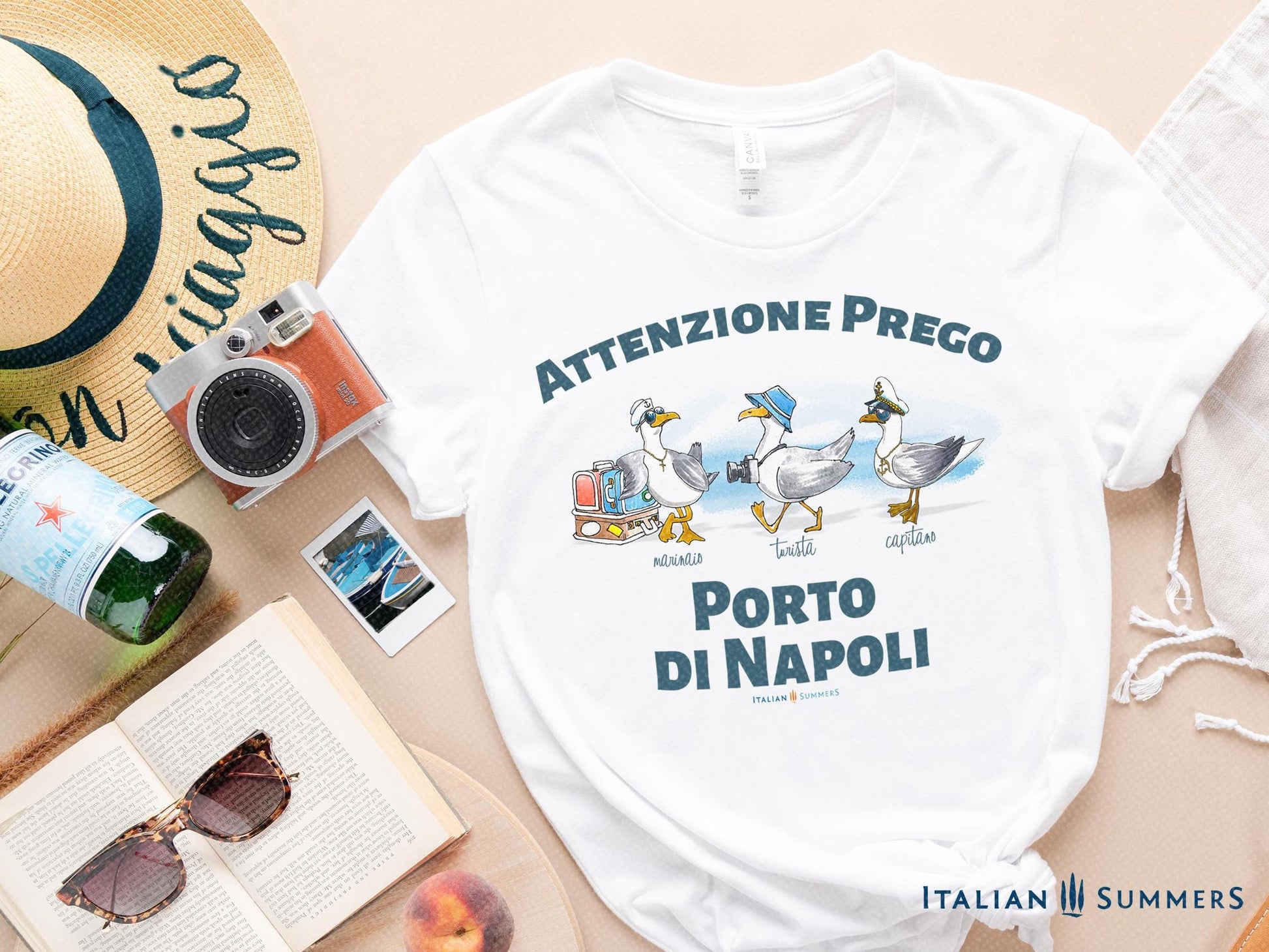 A cotton T-Shirt with the Italian text PORTO di NAPOLI in blue block letters and featuring the hand-drawn sketches of  three seagulls dressed up as a sailor, a tourist, and a boat captain.