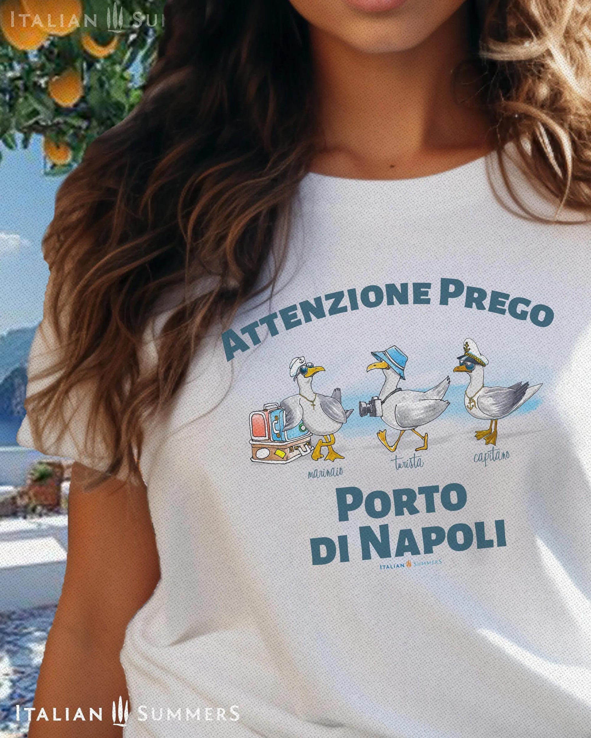 A cotton T-Shirt with the Italian text PORTO di NAPOLI in blue block letters and featuring the hand-drawn sketches of  three seagulls dressed up as a sailor, a tourist, and a boat captain.