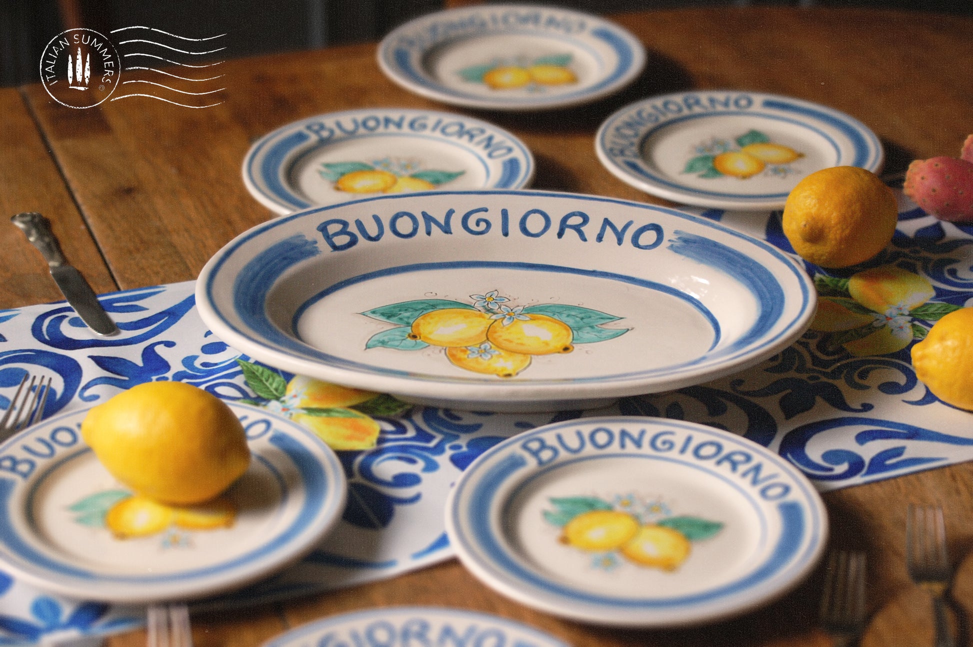 Ceramic plate Buongiorno Limoni handpainted in Sicily. This plate has the quote Biongiorno on the rim - handpainted - And colorfull lemons on the center of the plate with lemon flowers. On the rim of the plate there are blue paint stripes. The blue color is ultra marine. This plate is designed and sold by Italian Summers.