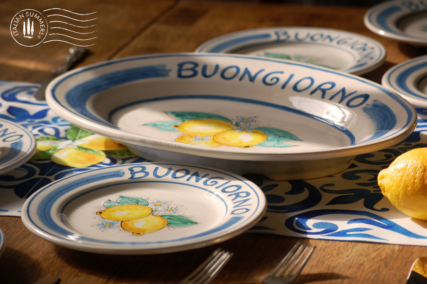 Ceramic plate Buongiorno Limoni handpainted in Sicily. This  plate has the quote Biongiorno on the rim - handpainted  - And colorfull lemons on the center of the plate  with lemon flowers. On the rim of the plate there are blue paint stripes. The blue color is ultra marine. This plate is designed and sold by Italian Summers.