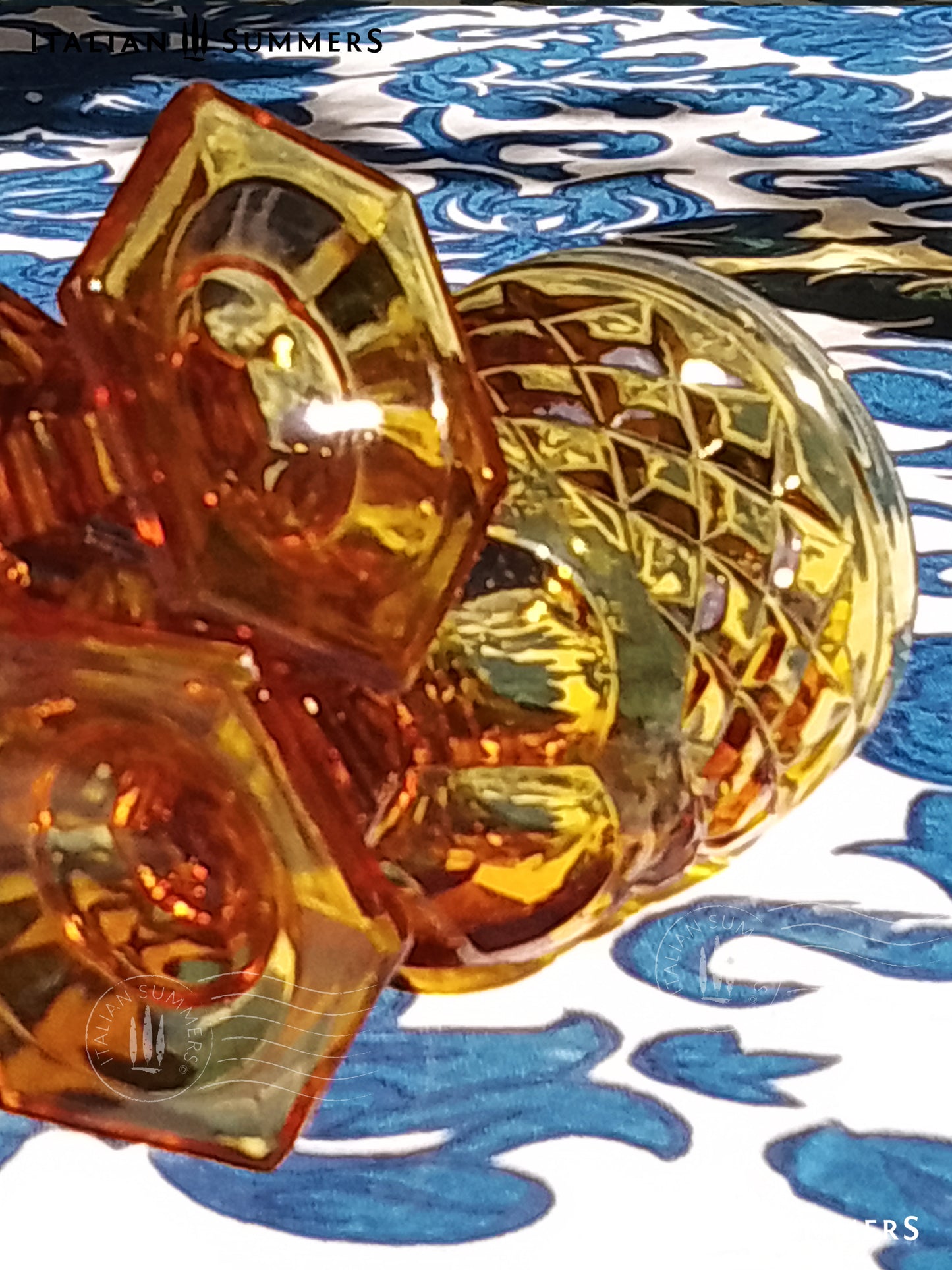 Set of Italian amber glass goblets and a carafe with the original Bormioli box on a floral patterned tablecloth.
