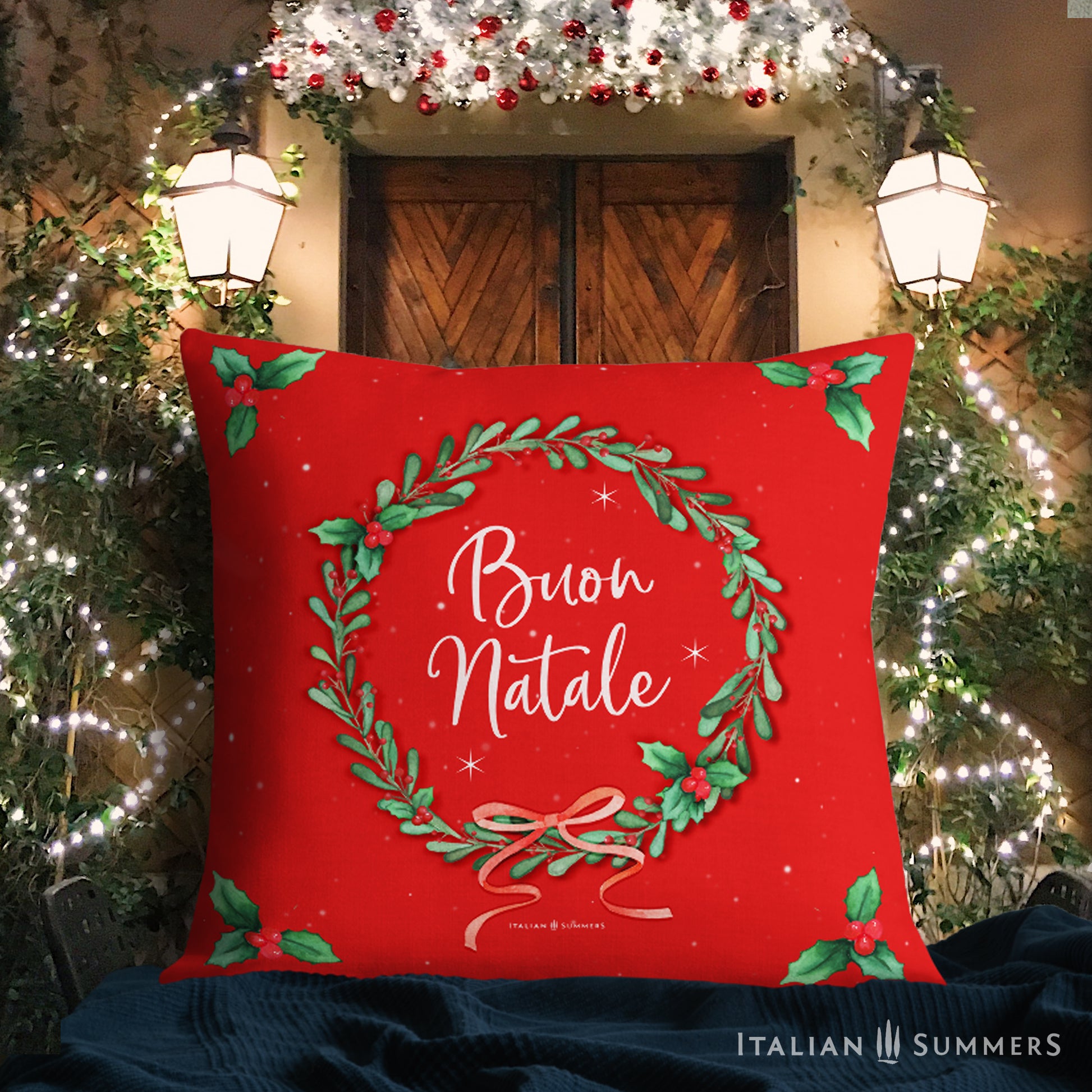Italyy Christmas red pillow with 'Buon Natale' text and Christmas wreath design, set against a festive Italian Village street background.