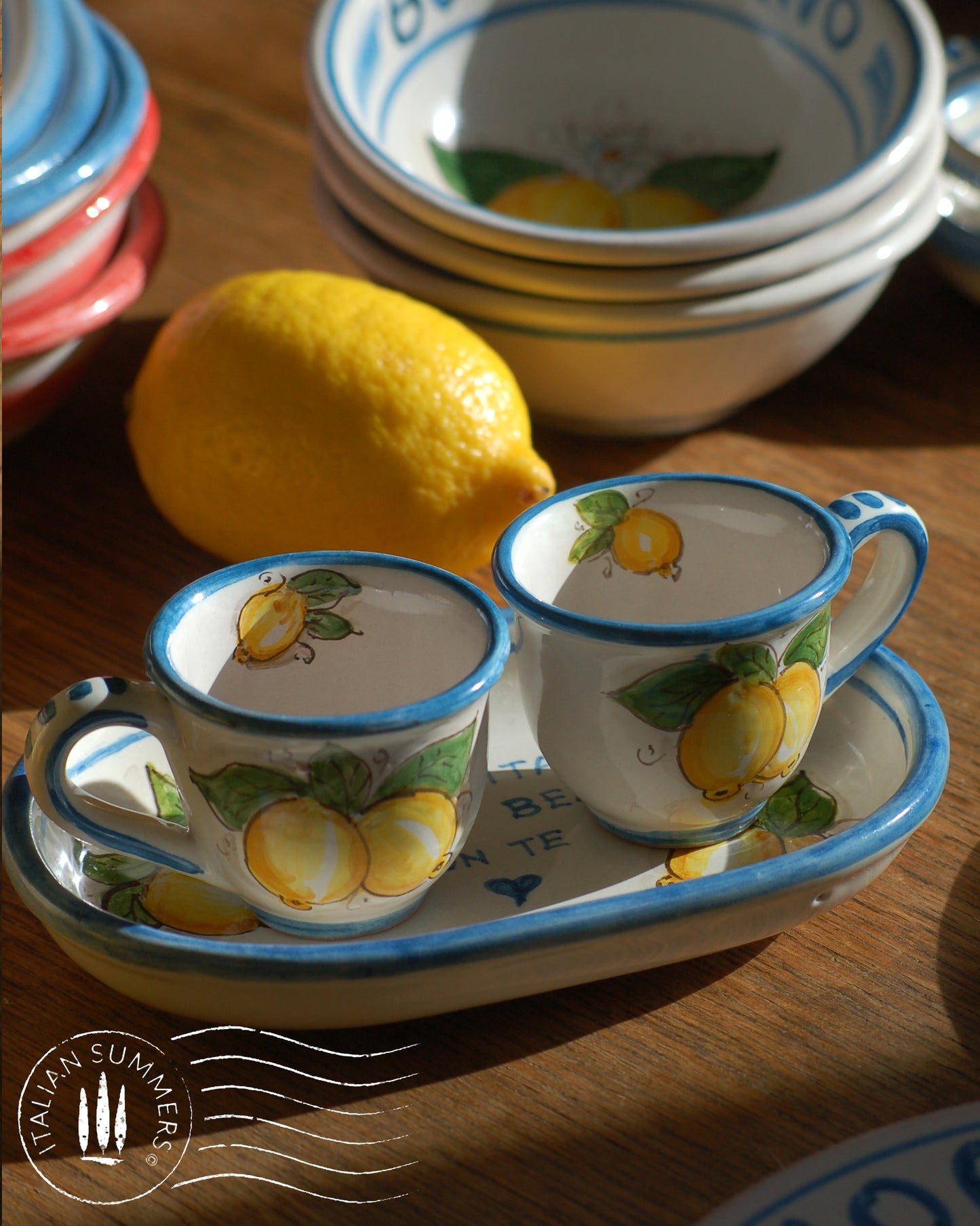 A bright and colorful Italian Maiolica ceramic espresso coffee set, two demitasse and a serving tray featuring sunny Sicilian lemons and a blue decoration with the Italian text -La vita e' piu bella con te-. hand made in Sicily