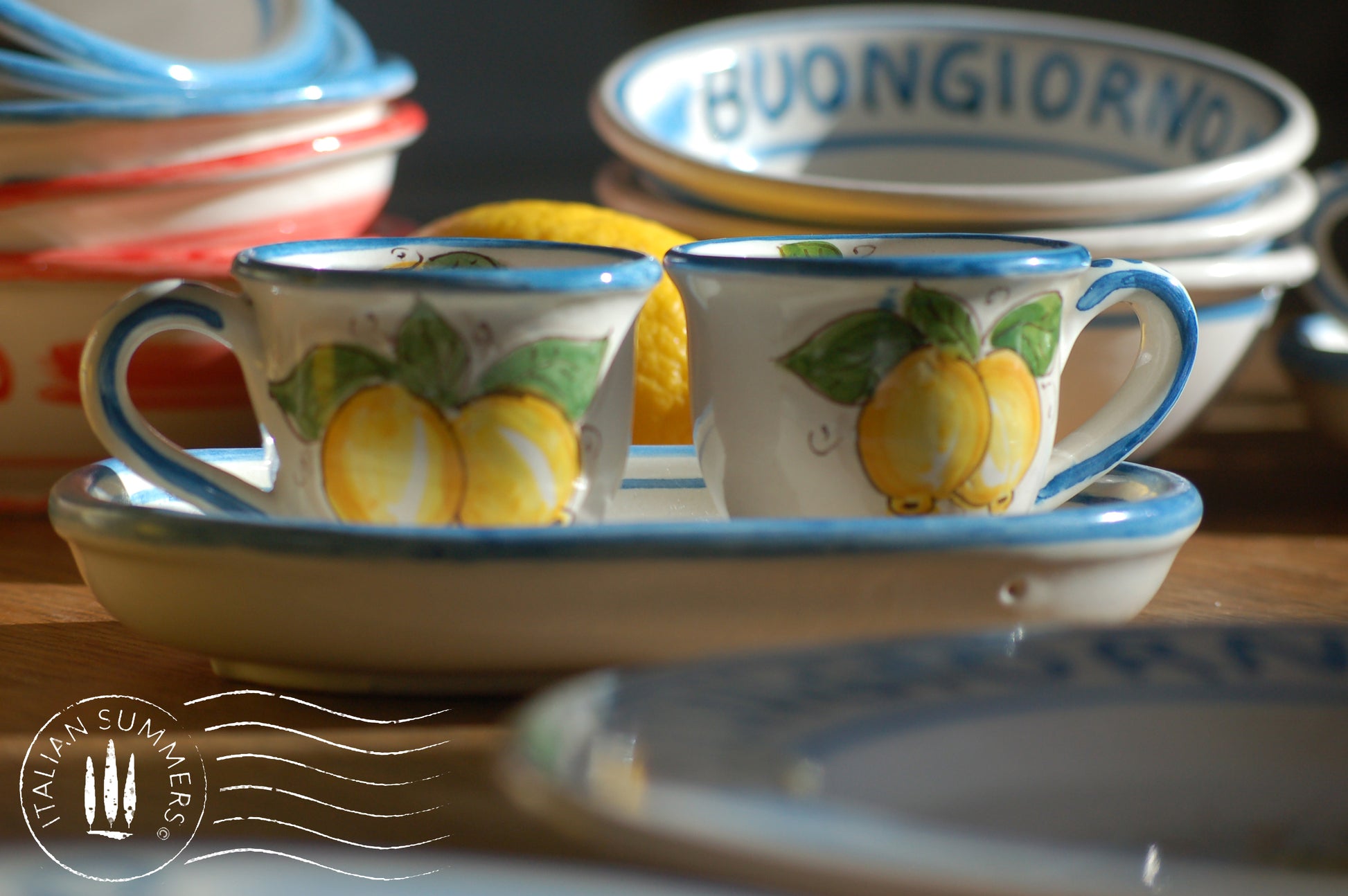 A bright and colorful Italian Maiolica ceramic espresso coffee set, two demitasse and a serving tray featuring sunny Sicilian lemons and a blue decoration with the Italian text -La vita e' piu bella con te-.  hand made in Sicily