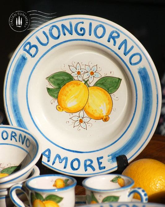A bright and colorful Maiolica ceramic plate, hand made in Sicily featuring sunny Sicilian lemons and a blue decoration with the text, Buongiorno Amore, which means, Good Morning my Love in Italian.