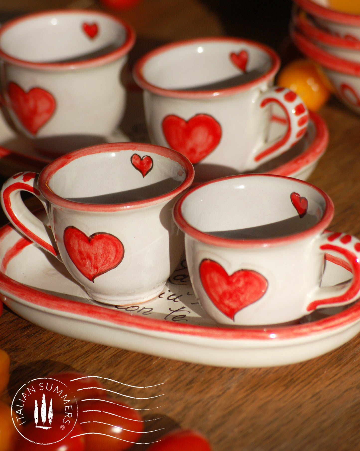 A bright and colorful Italian Maiolica ceramic espresso coffee set, two demitasse and a serving tray featuring happy Sicilian red hearts and a decoration with the Italian text -La vita e' piu bella con te-. hand made in Sicily