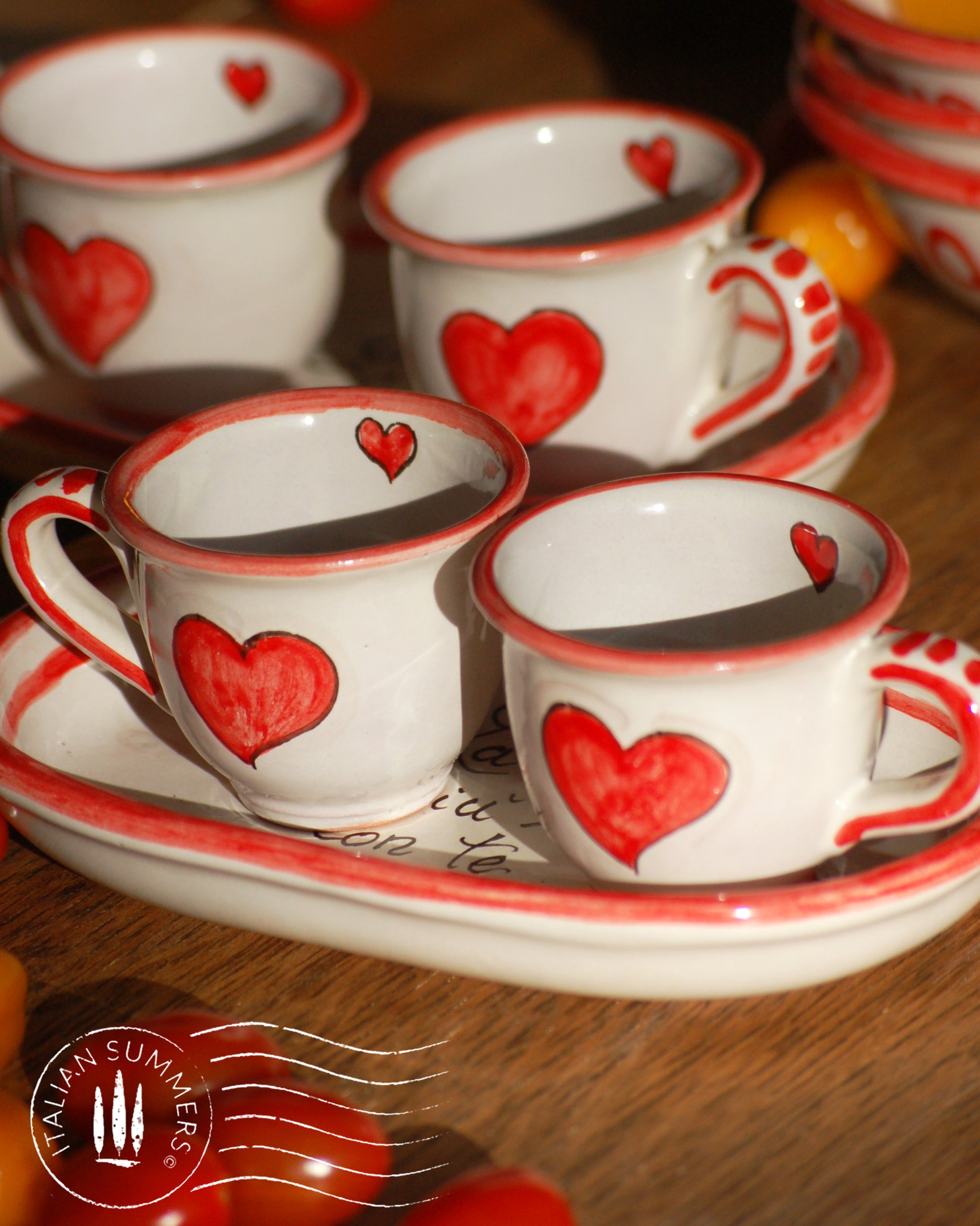 A bright and colorful Italian Maiolica ceramic espresso coffee set, two demitasse and a serving tray featuring happy Sicilian red hearts and a decoration with the Italian text -La vita e' piu bella con te-.  hand made in Sicily
