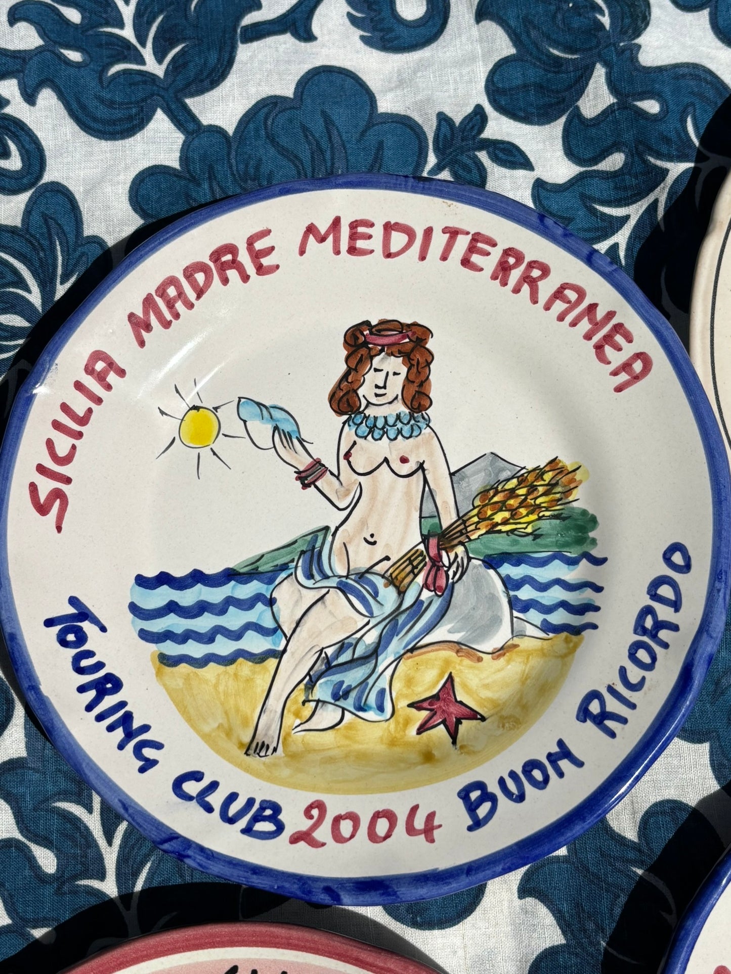 Italian decorative vintage plate with a woman holding a sea shell and wheat, text 'Sicilia Mare Mediterranea' and 'Touring Club 2004 Buon Ricordo'.