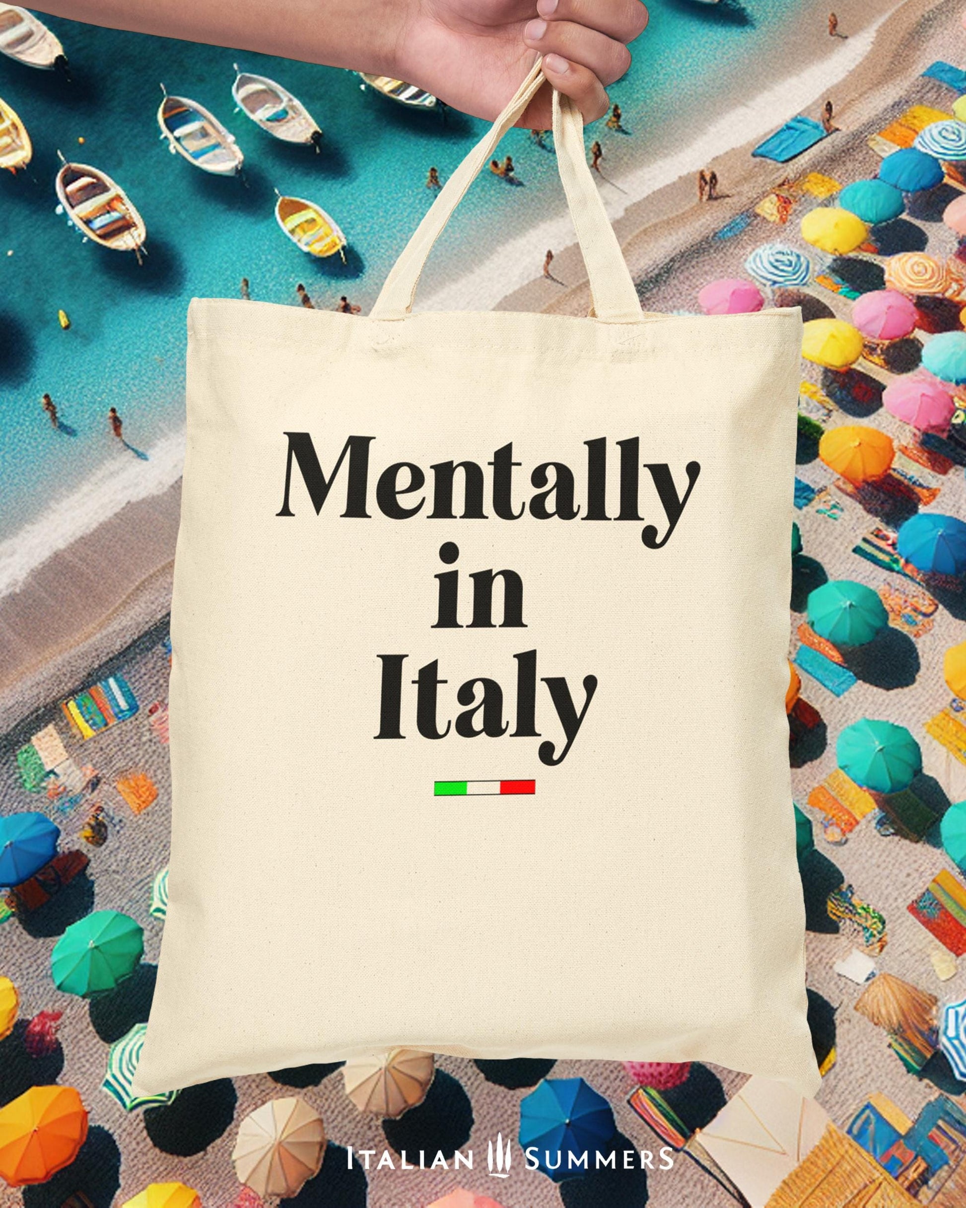 Italy canvas tote bag with the text Mentally in Italy. Under the text you see a little bar with the happy colors of the Italian flag. The text of the quote is in black. Designed by Italian Summers