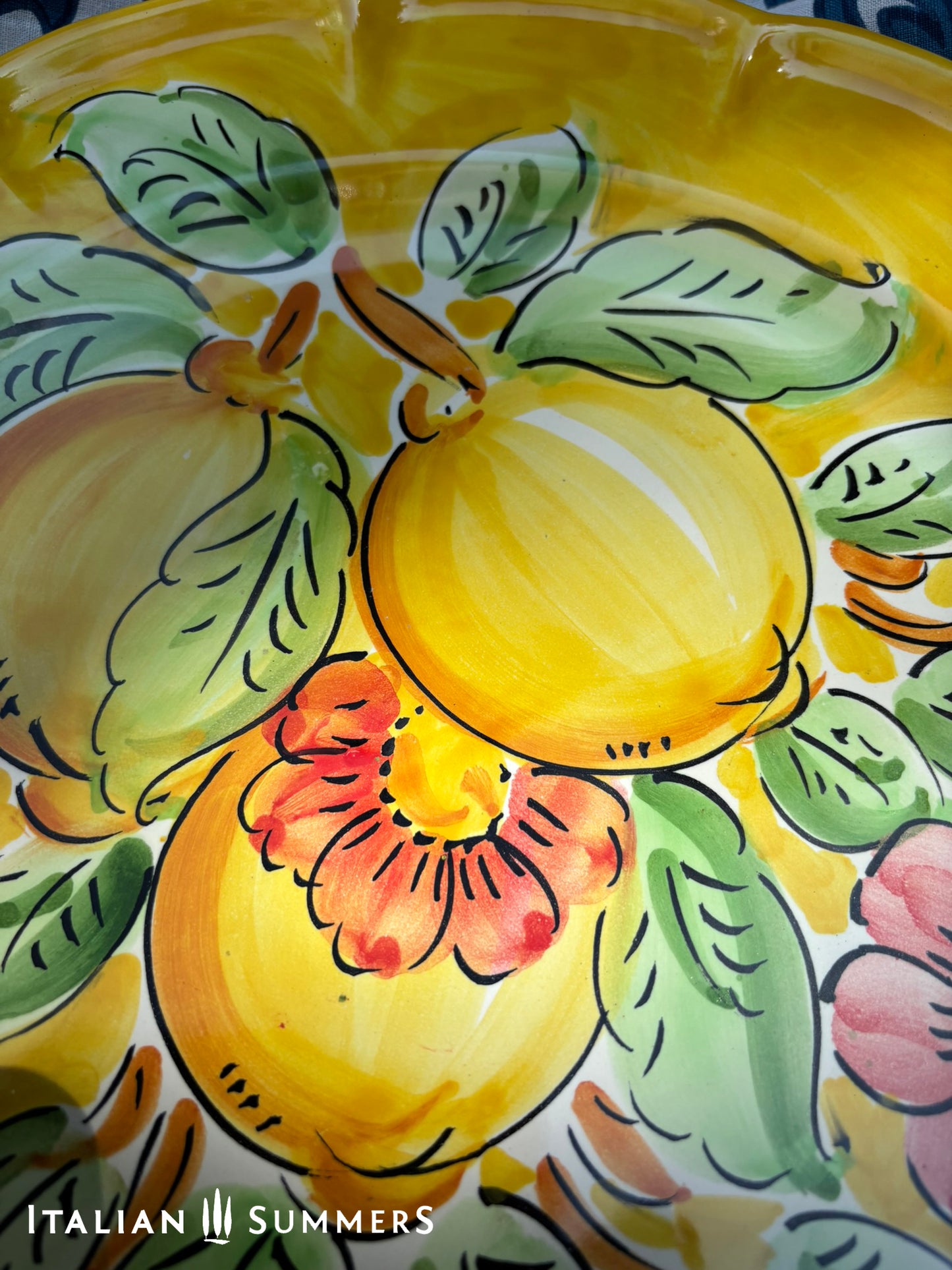 Italian Vietri Decorative ceramic plate with lemon design on a floral patterned fabric background