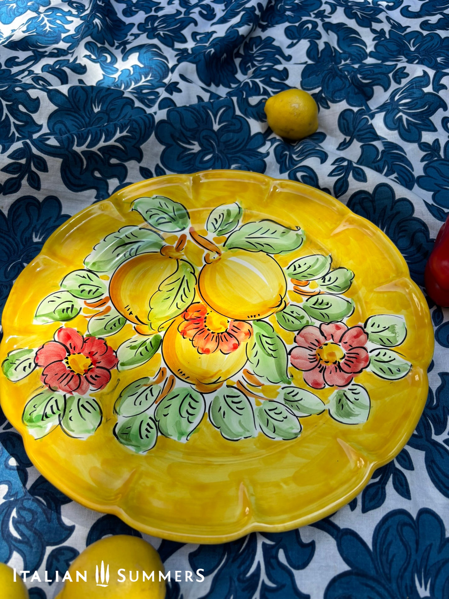 Italian Vietri Decorative ceramic plate with lemon design on a floral patterned fabric background