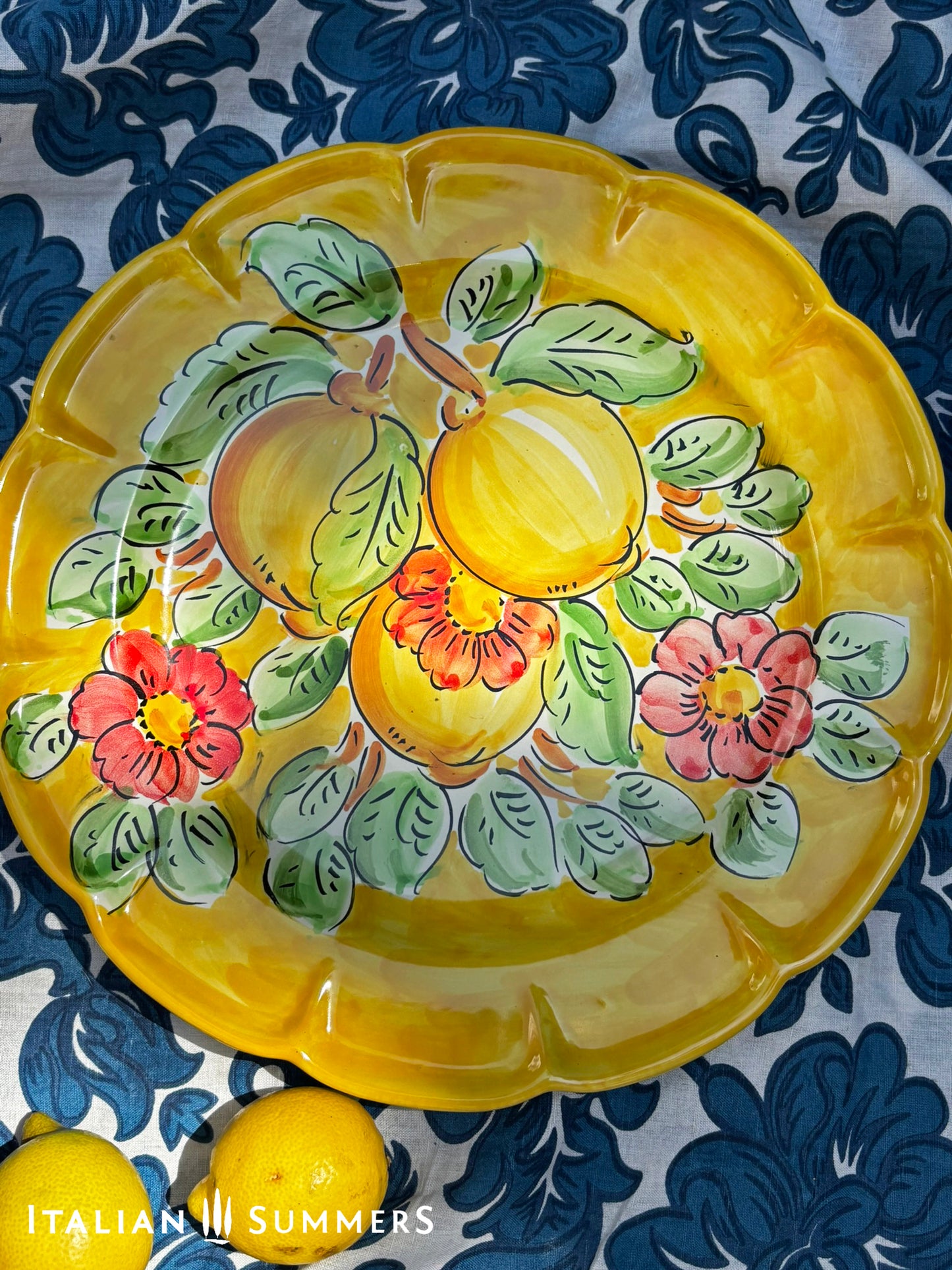 Italian Vietri Decorative ceramic plate with lemon design on a floral patterned fabric background