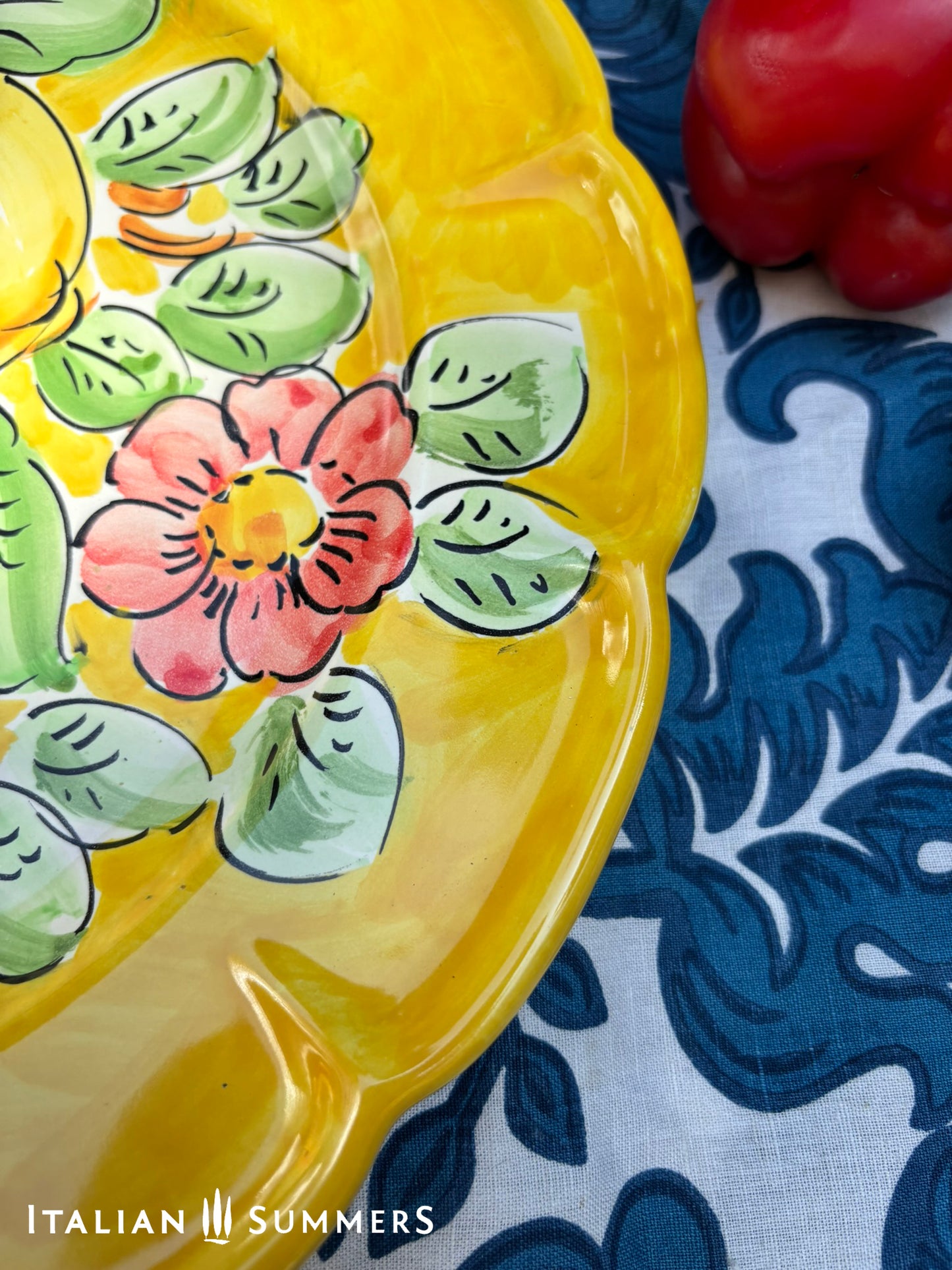 Italian Vietri Decorative ceramic plate with lemon design on a floral patterned fabric background