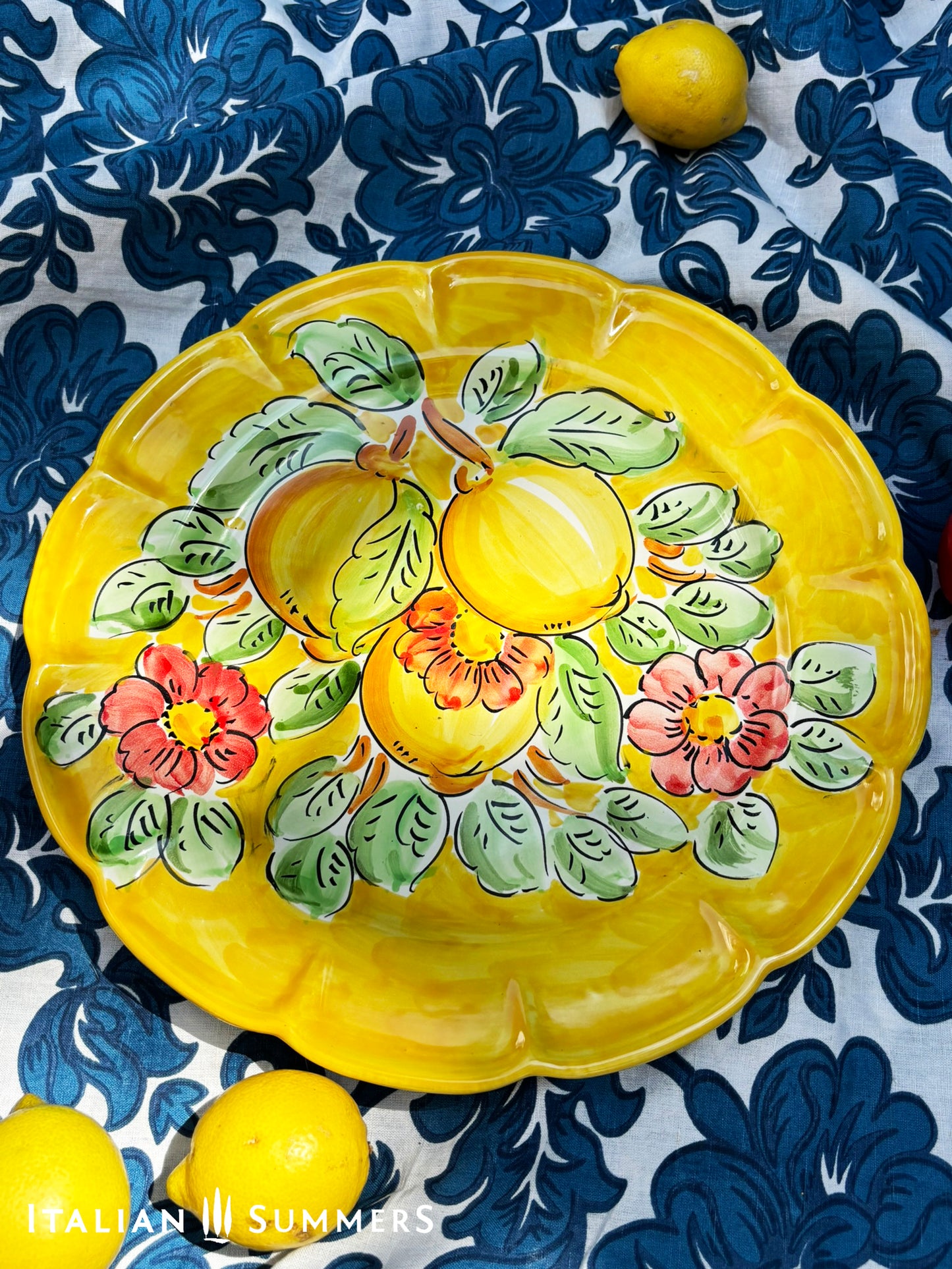 Italian Vietri Decorative ceramic plate with lemon design on a floral patterned fabric background