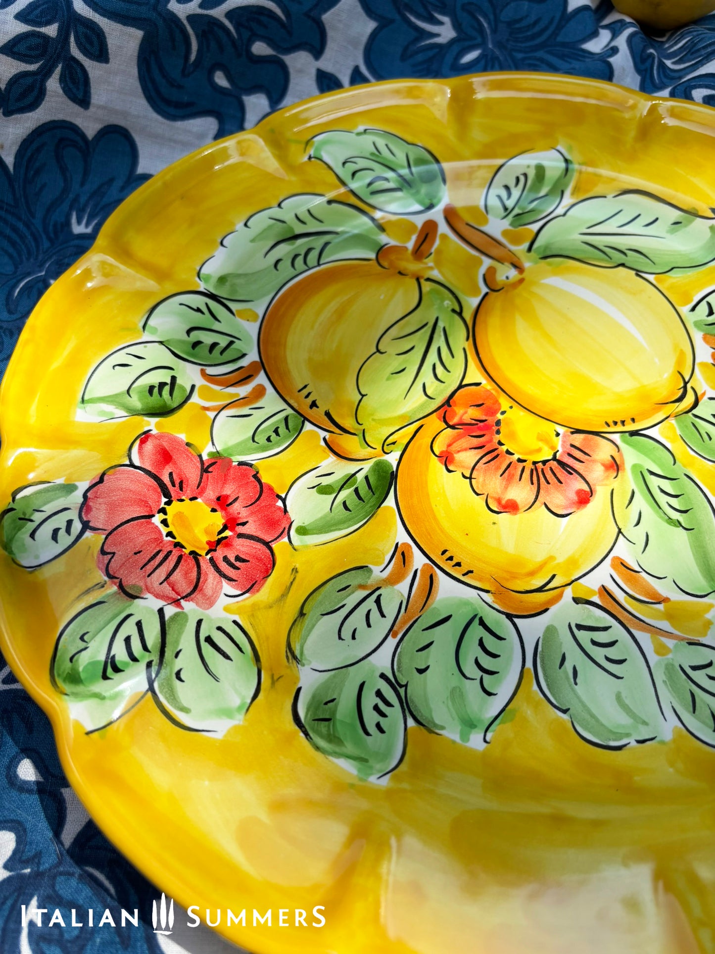 Italian Vietri Decorative ceramic plate with lemon design on a floral patterned fabric background