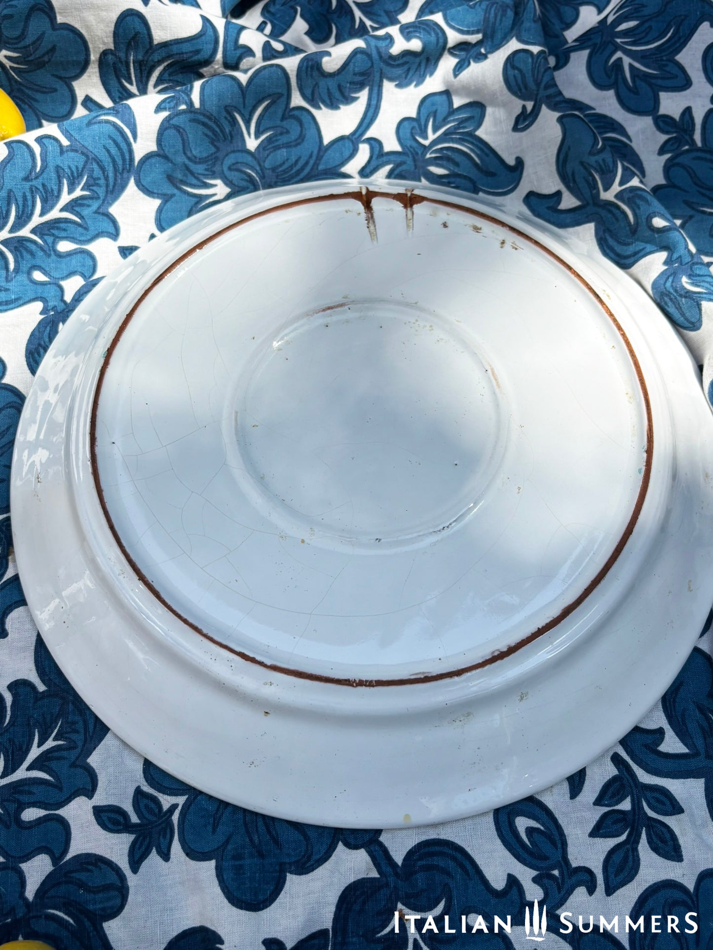 A large Sicilian vintage serving or Decorative plate with 'Spaghettata"' text and pear and cherries traditional Sicilian Maiolica illustration, on a blue floral patterned background.
