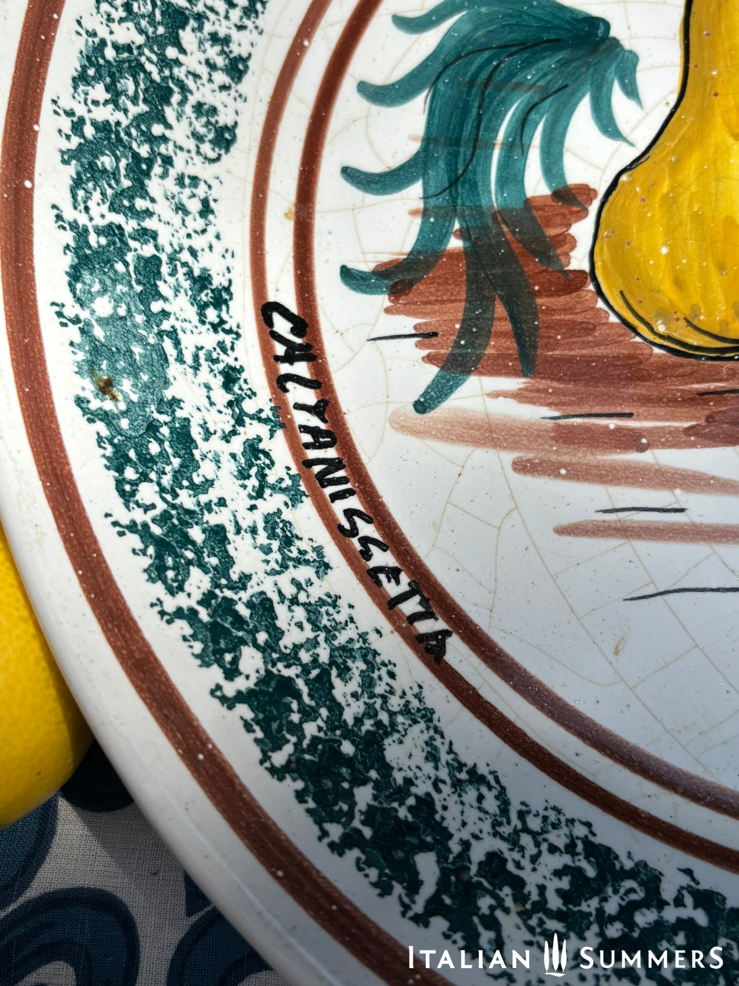 A large Sicilian vintage serving or Decorative plate with 'Spaghettata"' text and pear and cherries traditional Sicilian Maiolica illustration, on a blue floral patterned background.
