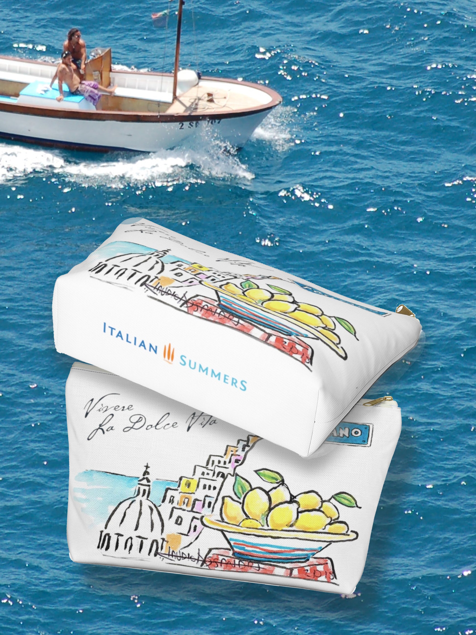 Italy inspired clutch of white canvas with the text Vivere La Dolce Vita which means Living La Dolce Vita. The clutch is decorated with a sketch of a part of Positano, the cupola of the church and some ice cream colored houses seen from the side and a big ceramic bowl of Amalfi Coast lemons, there is also a streetsign which sais Positano. Designed by Italian Summers