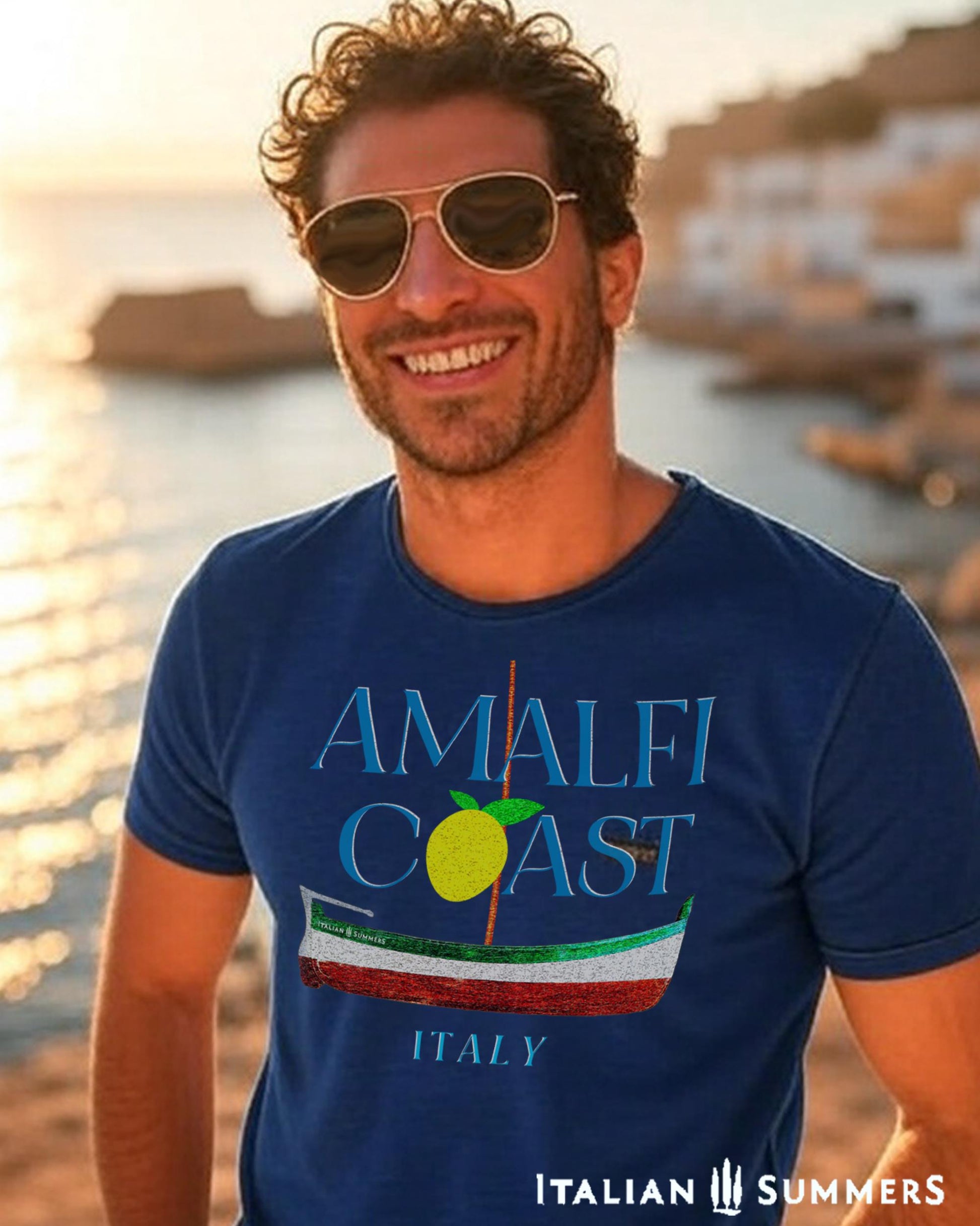 A smiling  tanned Italian man is standing in front of the sea in a seaside Village in the Amalfi Coast, possibly Positano. Behind him is a light blue vintage vespa. He is  wearing a Navy-colored T shirt with light blue text: AMALFI COAST.  the O in Coast is a yellow stylized lemon with two leaves.
Under the text is a traditional Amalfi coast boat called a Gozzo, in traditional colors of the Italian flag, green, white, red.
The word light blue text of the word ITALY on the bottom.