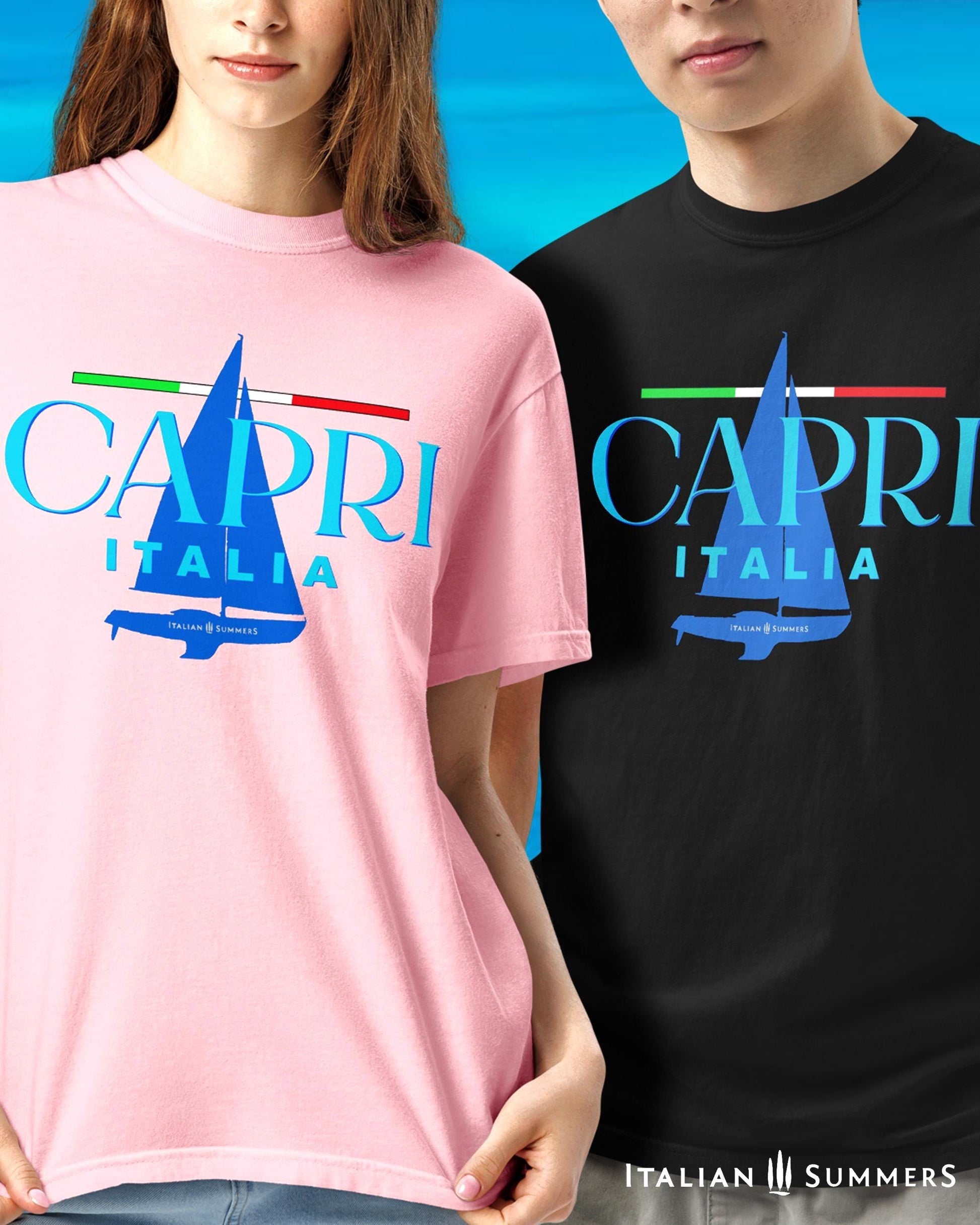 A couple wearing a light pink  and a navy T shirt, with a frontal prints featuring a marine blue silhouette of a sailboat and a large text: CAPRI, ITALIA, with a thin Italian flag as a chevron, looking like a sailing shirt for sportsmen or Mediterranean Sea enthusiasts.