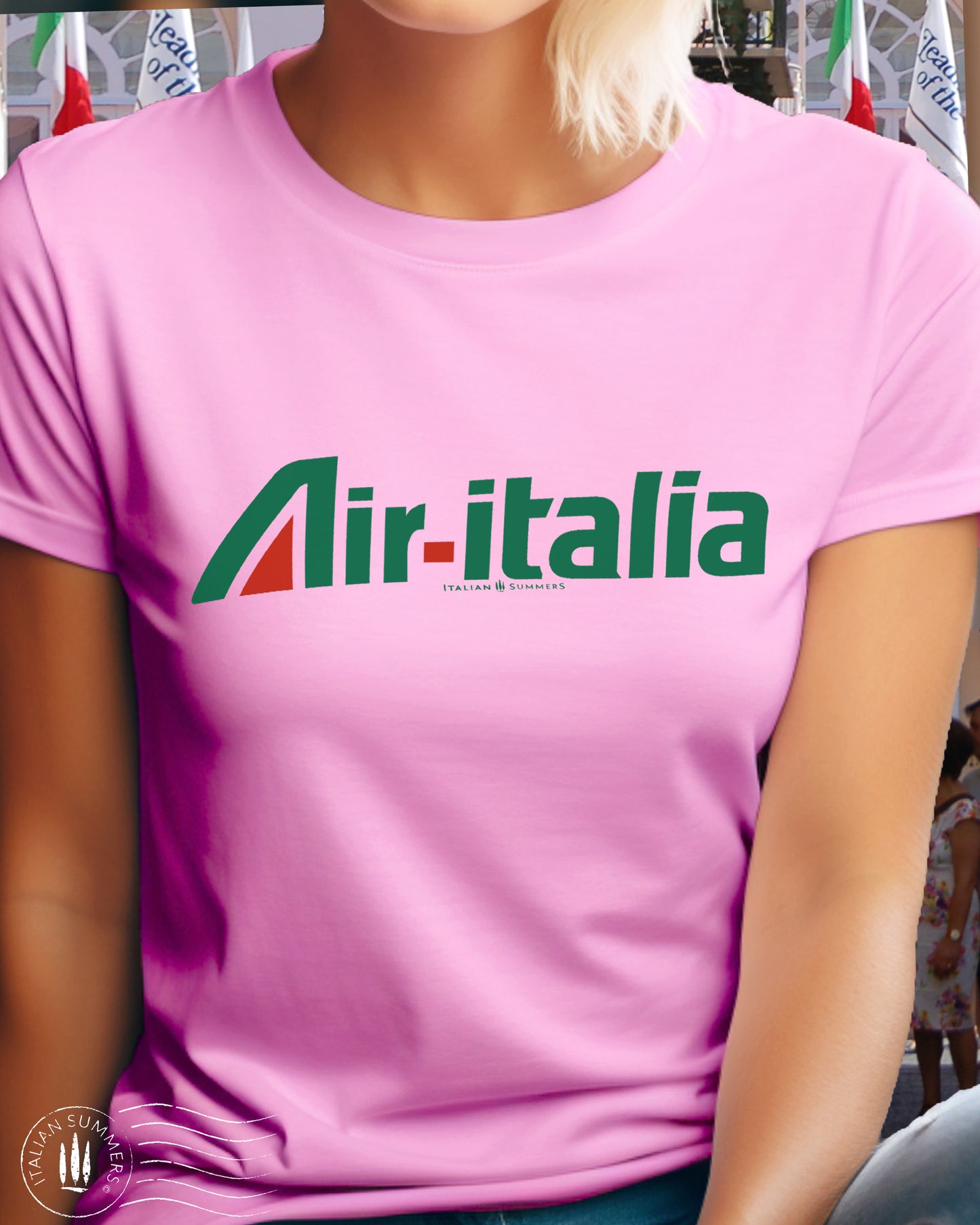 A girl is wearing an all cotton pink T-shirt with a large green and red Logo of Air-Italia airlines. A retro design of the nostalgic 1960s in Italy when Alitalia was the national airline. Sure to bring memories to Italy aficionados