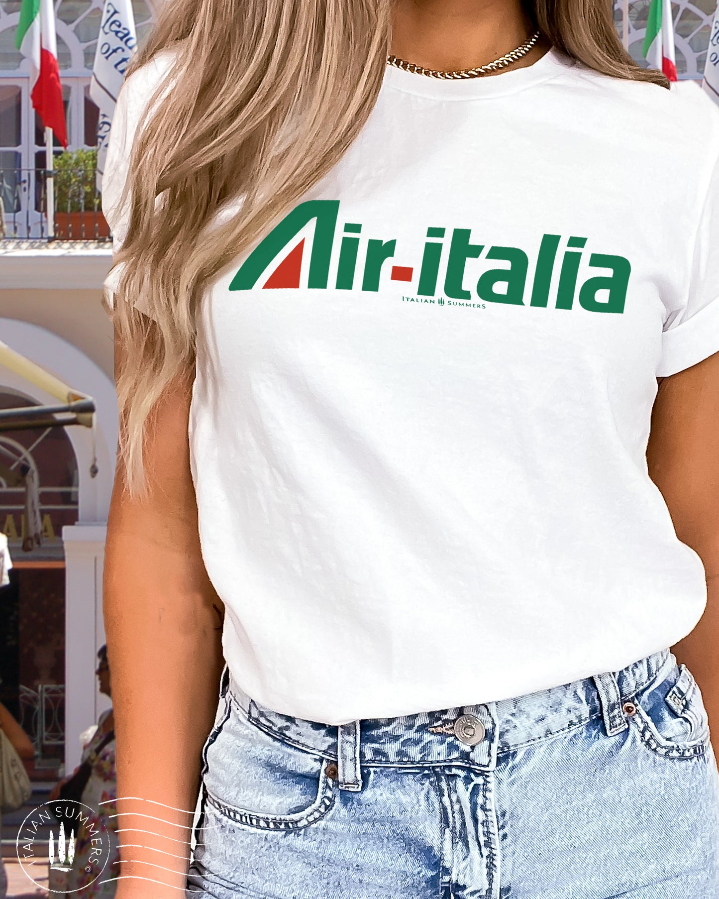 A girl is wearing an all cotton white shirt with a large green and red Logo of Air-Italia airlines. A retro design of the nostalgic 1960s in Italy when Alitalia was the national airline. Sure to bring memries to Italy aficionados