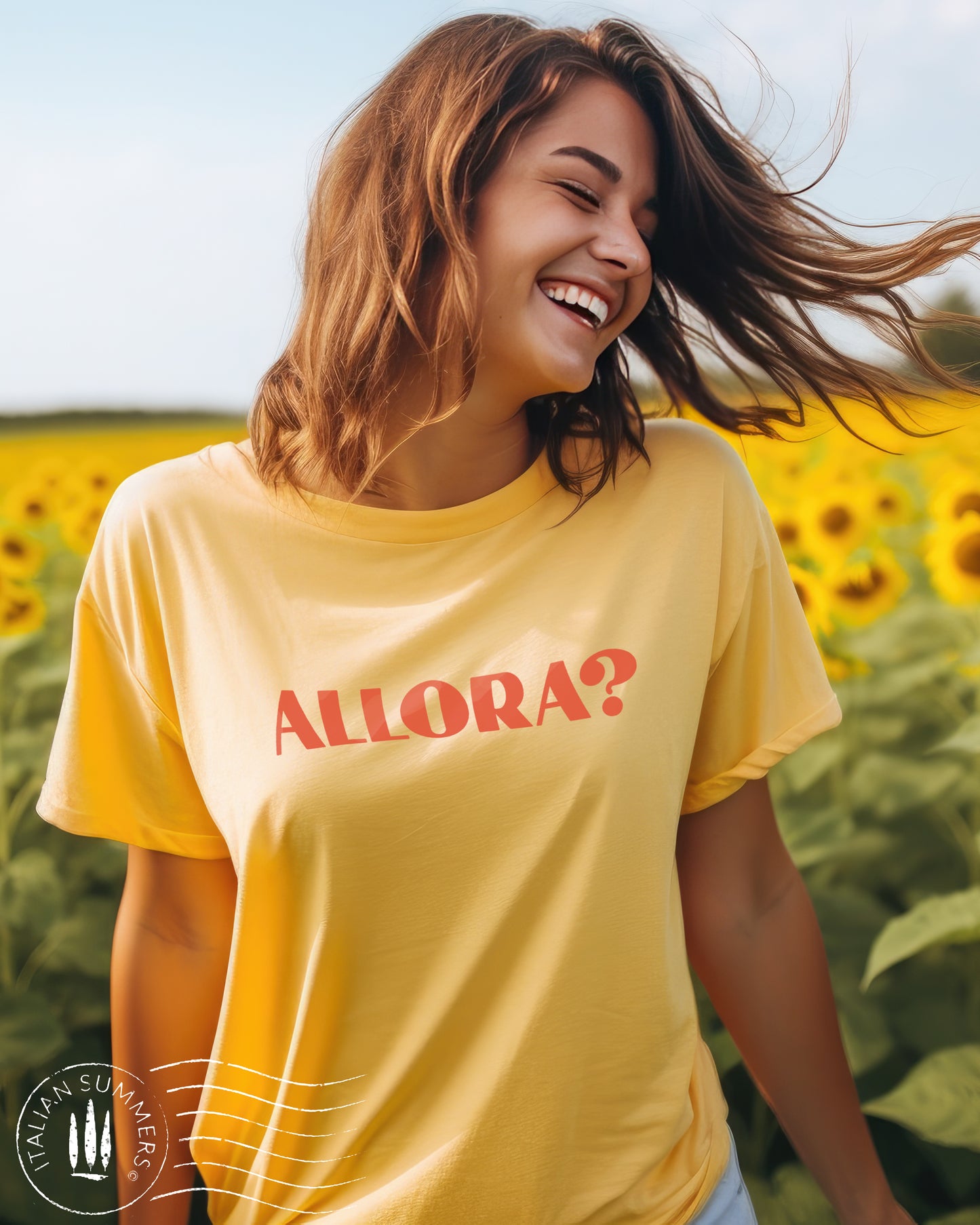 A girl stands in a field of Italian sunflowers. She wears a yellow Italy inspired t-shirt with a red text of the Italian expression: Allora?, Used all the time in Italian language. The color of the shirt is a soft pastel peach with the Allora expression in terra. Designed and sold by Italian Summers