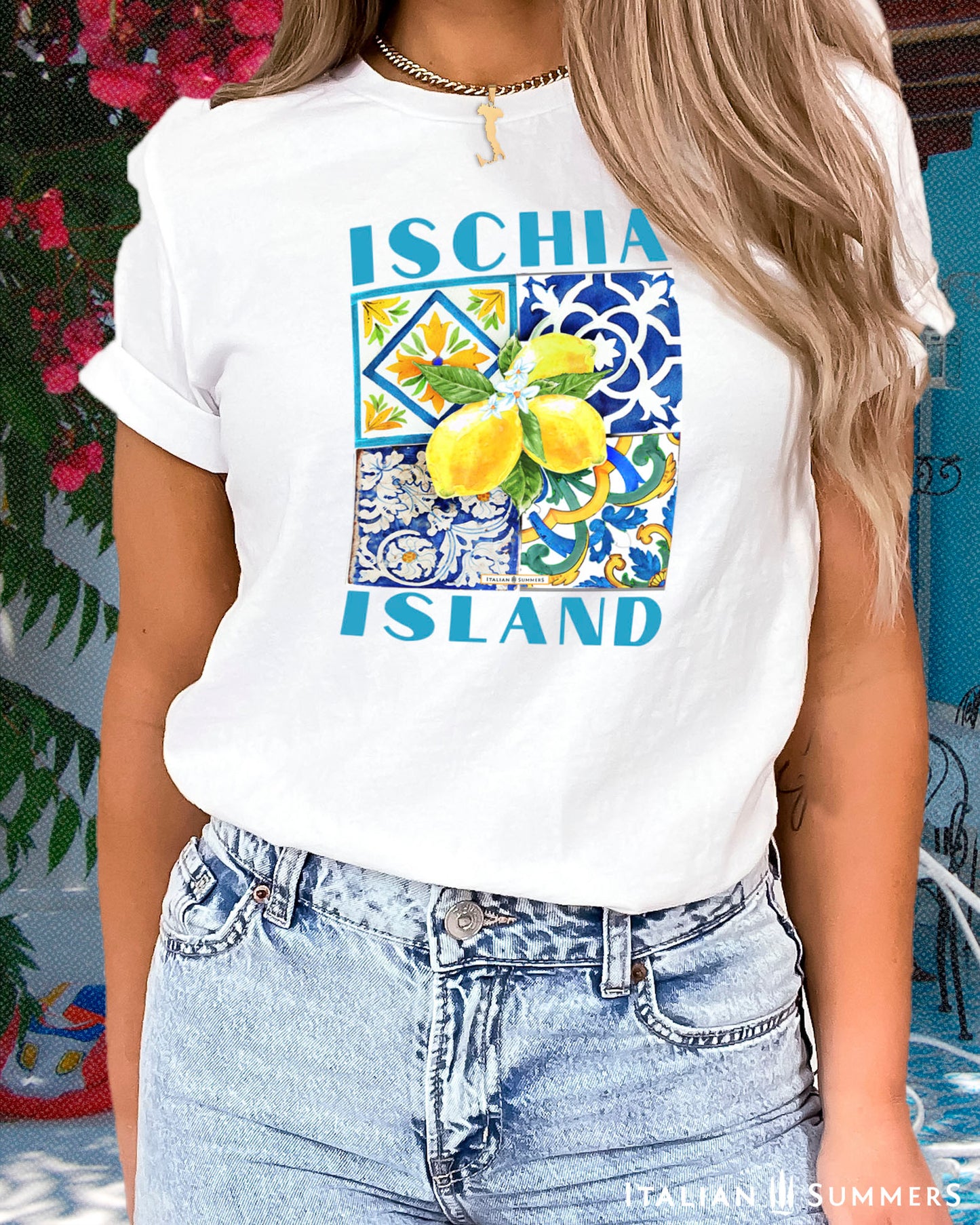 An all cotton T shirt with a Mediterranean tile design on the chest and a large cluster of Amalfi Coast lemons on top of the tiles. The lemons are bright yellow with green leaves and flowers. A blue text states: ISCHIA ISLAND