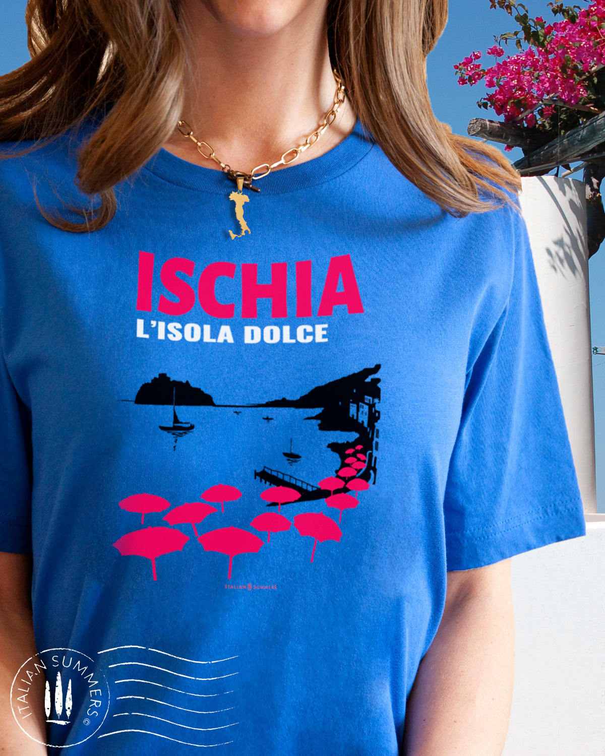 Italy Inspired garment dyed T Shirt with the text: ISCHIA L'isola dolce (Ischia, the sweet island) with the print of the island's beach with the famous Aragonese Castle in the backround, with colored beach umbrellas strewn in the foreground. Made by Italian Summers
