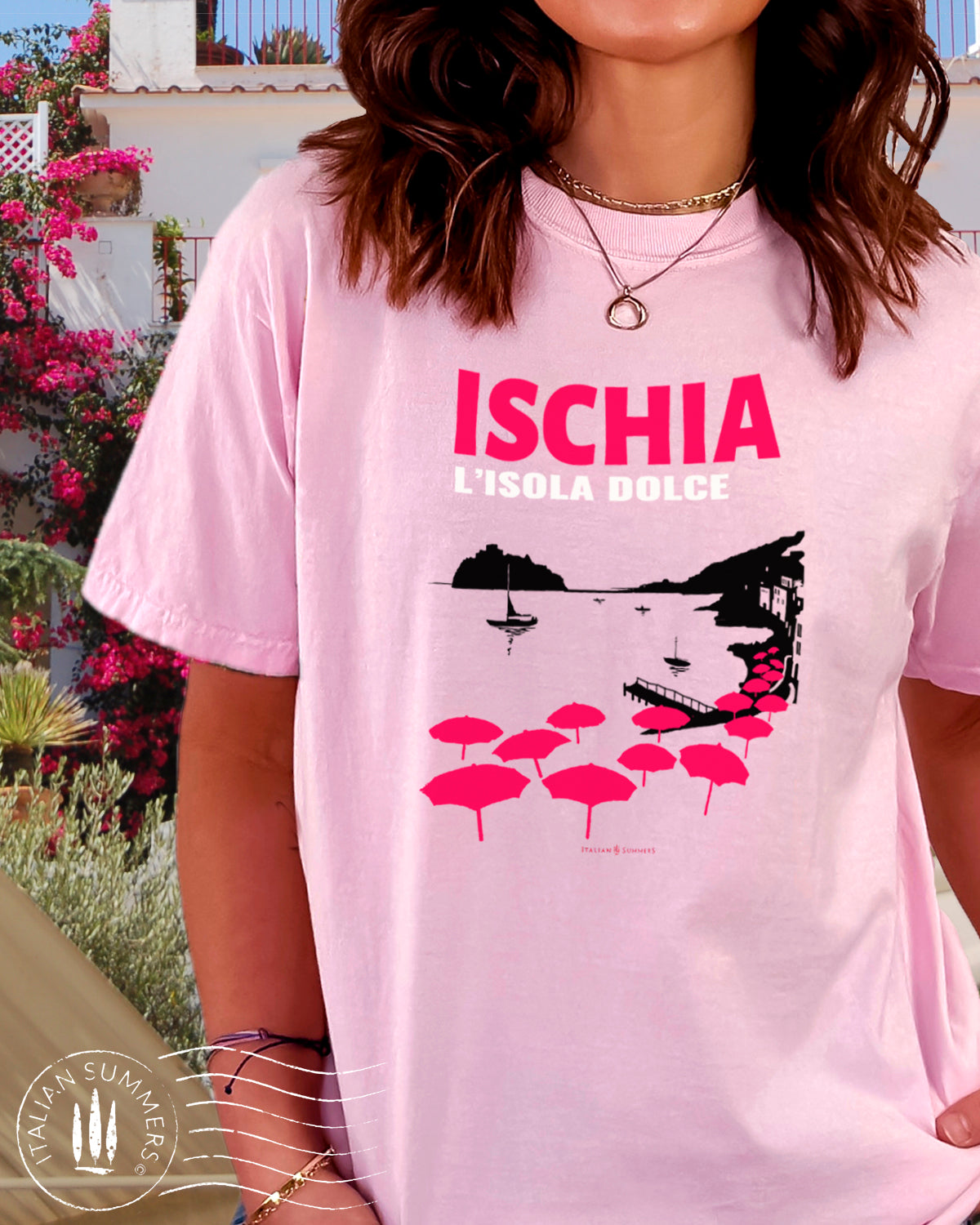 Italy Inspired garment dyed T Shirt with the text: ISCHIA L'isola dolce (Ischia, the sweet island) with the print of the island's beach with the famous Aragonese Castle in the backround, with colored beach umbrellas strewn in the foreground. Made by Italian Summers