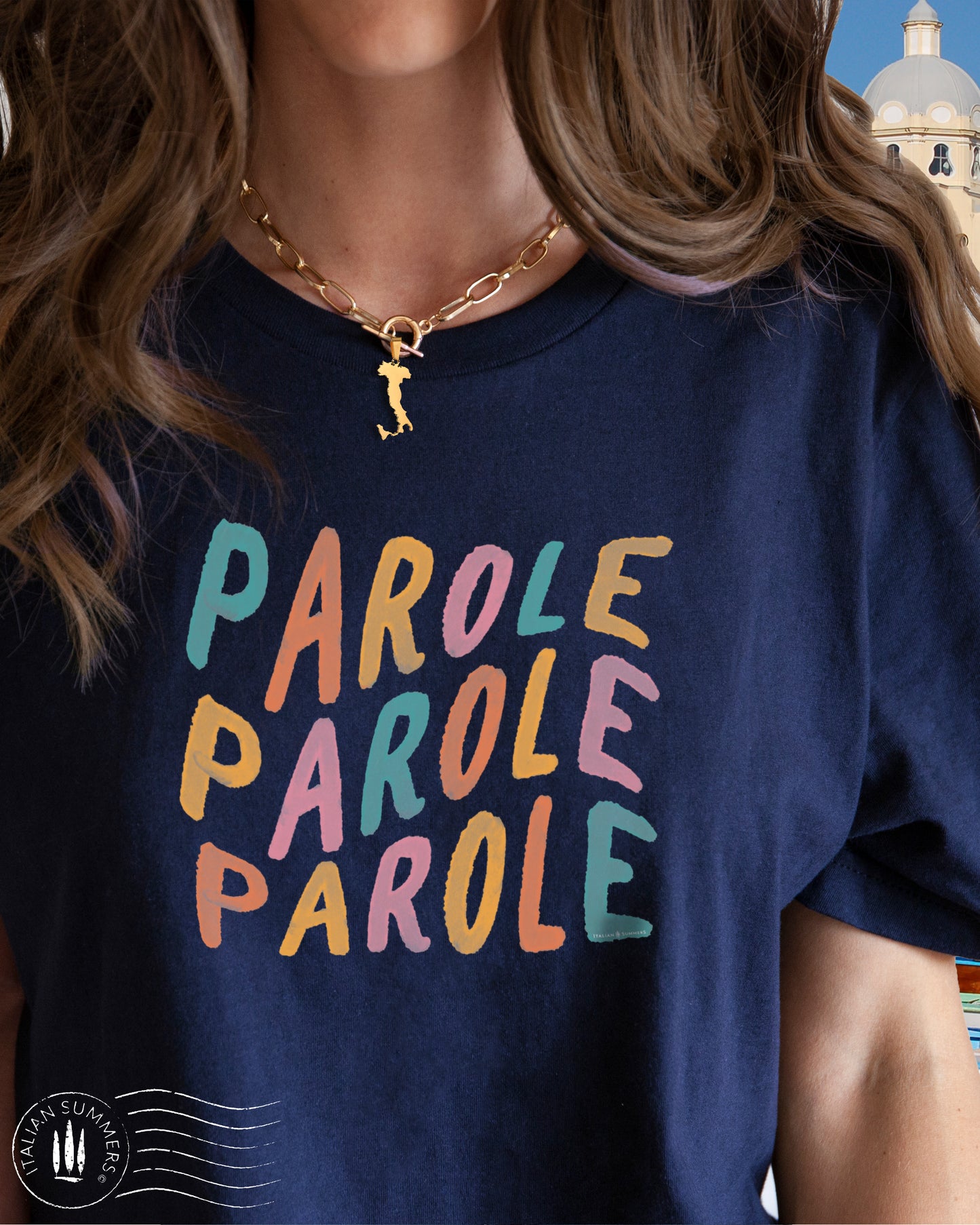 A girl is wearing an all-cotton navy blue t-shirt with a colorful Italian quote in soft pastel tones: 'parole, parole, parole', reminiscent of Mina's famous Fab 70s song. Perfect to evoke that cheerful feeling when you wear it!