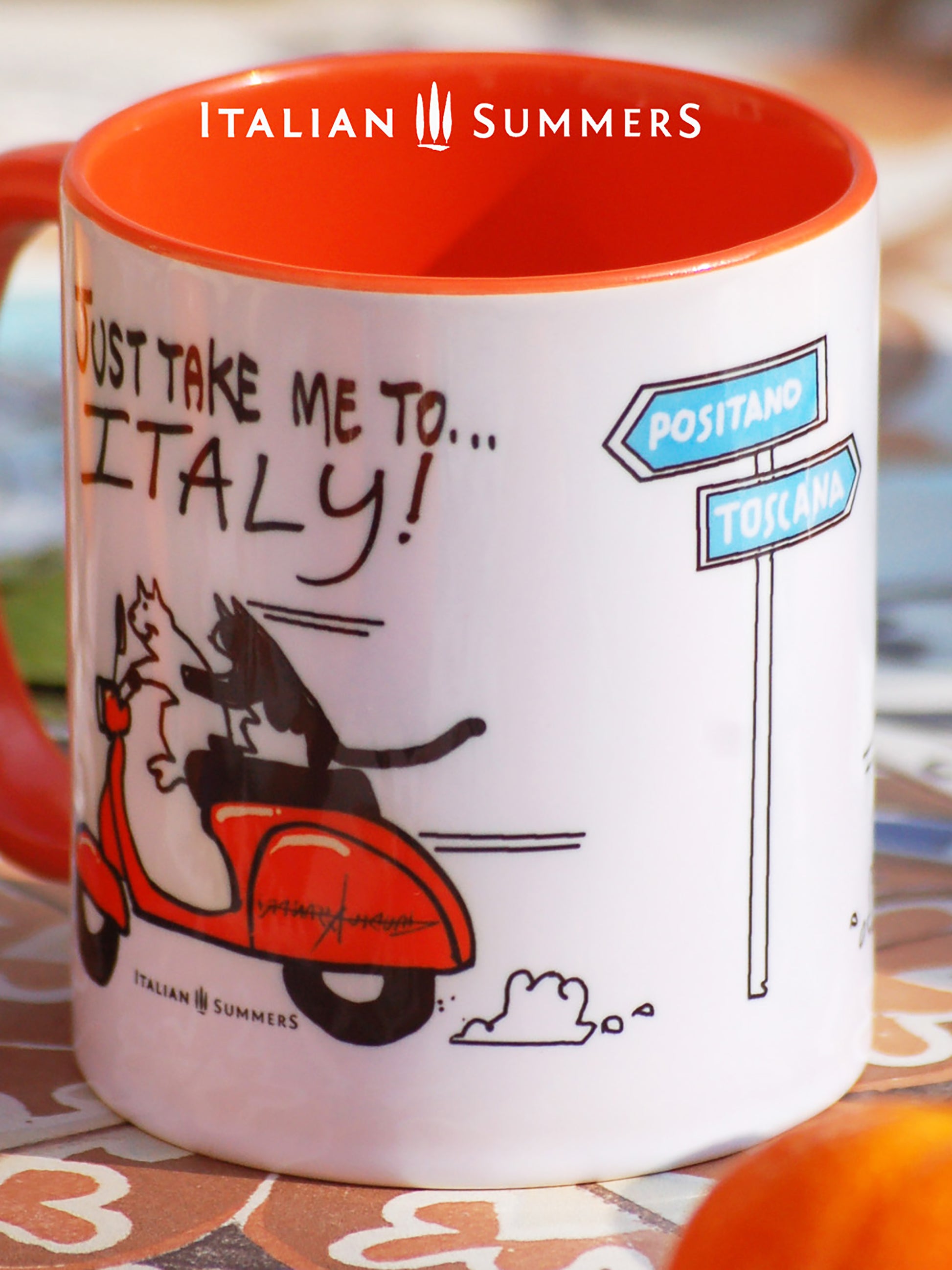 Italy inspired mug with a sketch of 2 cats driving on a vintage orange Vespa, with the quote "Just take me to Italy'. In the center of the mug is a sketch of a streetsign with the locations Positano and Tuscany. Made by Italian Summers