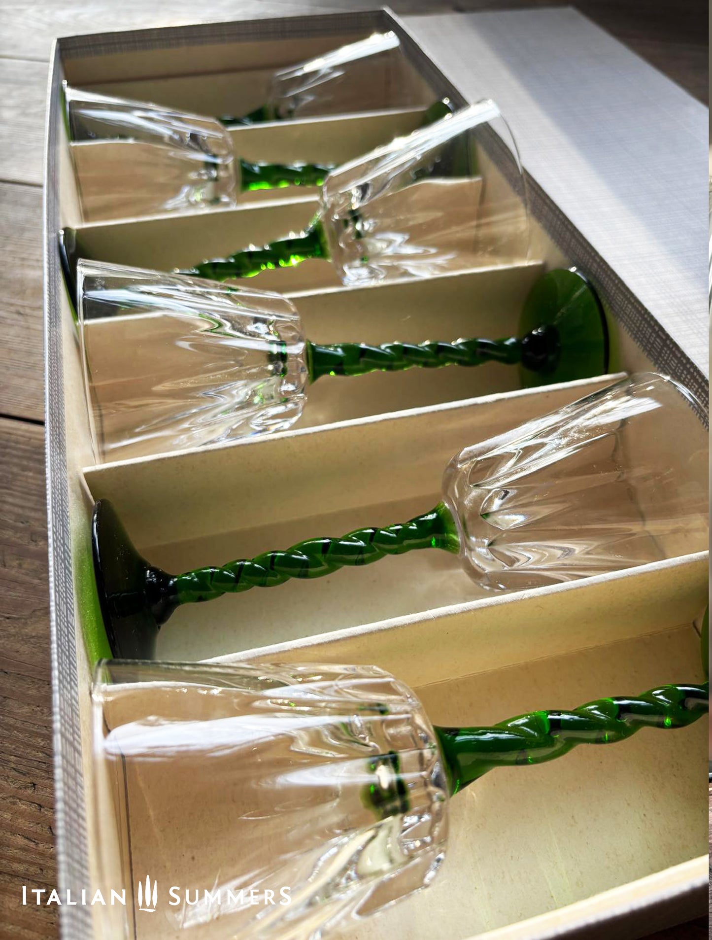 Set of glass wine glasses with green stems in a vintage carboard box, brand 'Italian Summers' visible.
