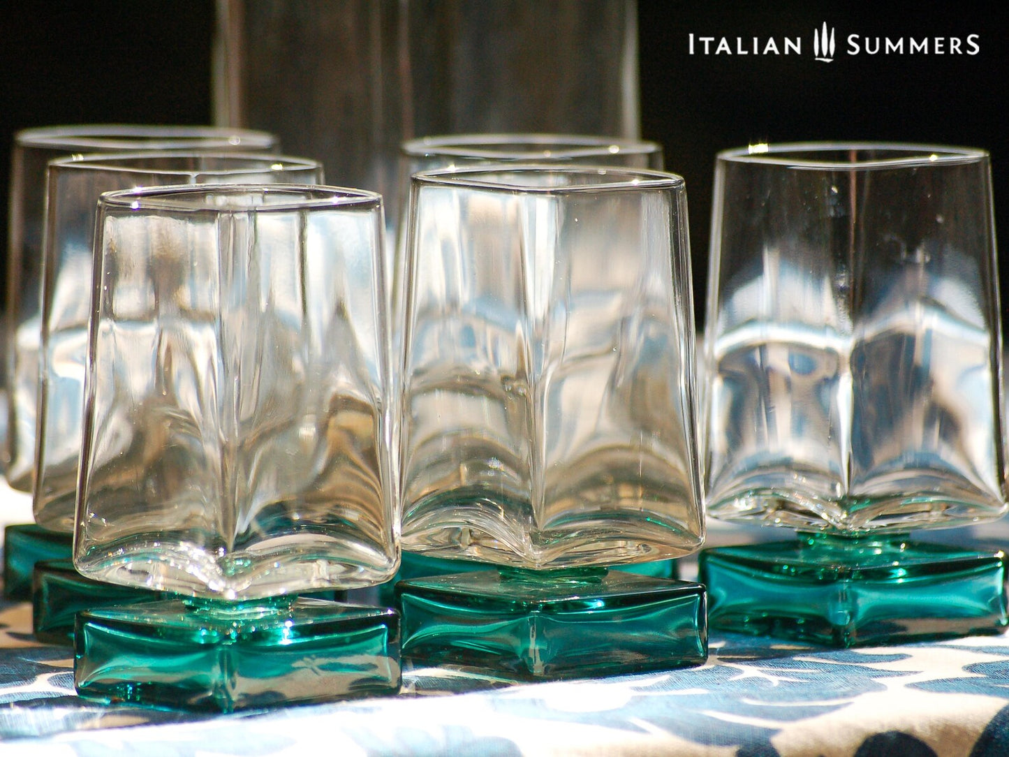 Vintage Bormioli Monet glass set from Italy, featuring square whiskey glasses with bold green foot and matching decanter, displayed on a table in retro style.