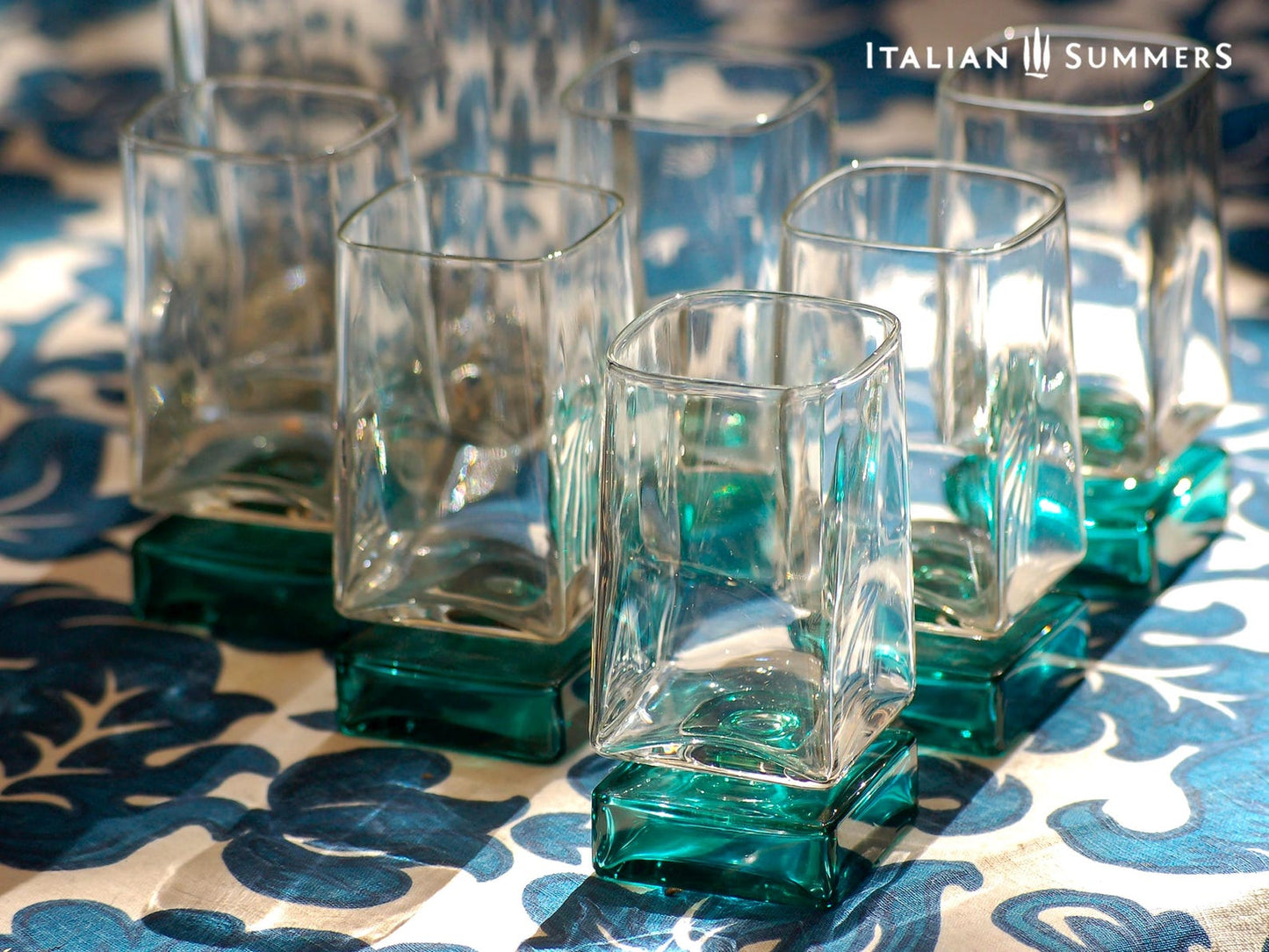 Vintage Bormioli Monet glass set from Italy, featuring square whiskey glasses with bold green foot and matching decanter, displayed on a table in retro style.