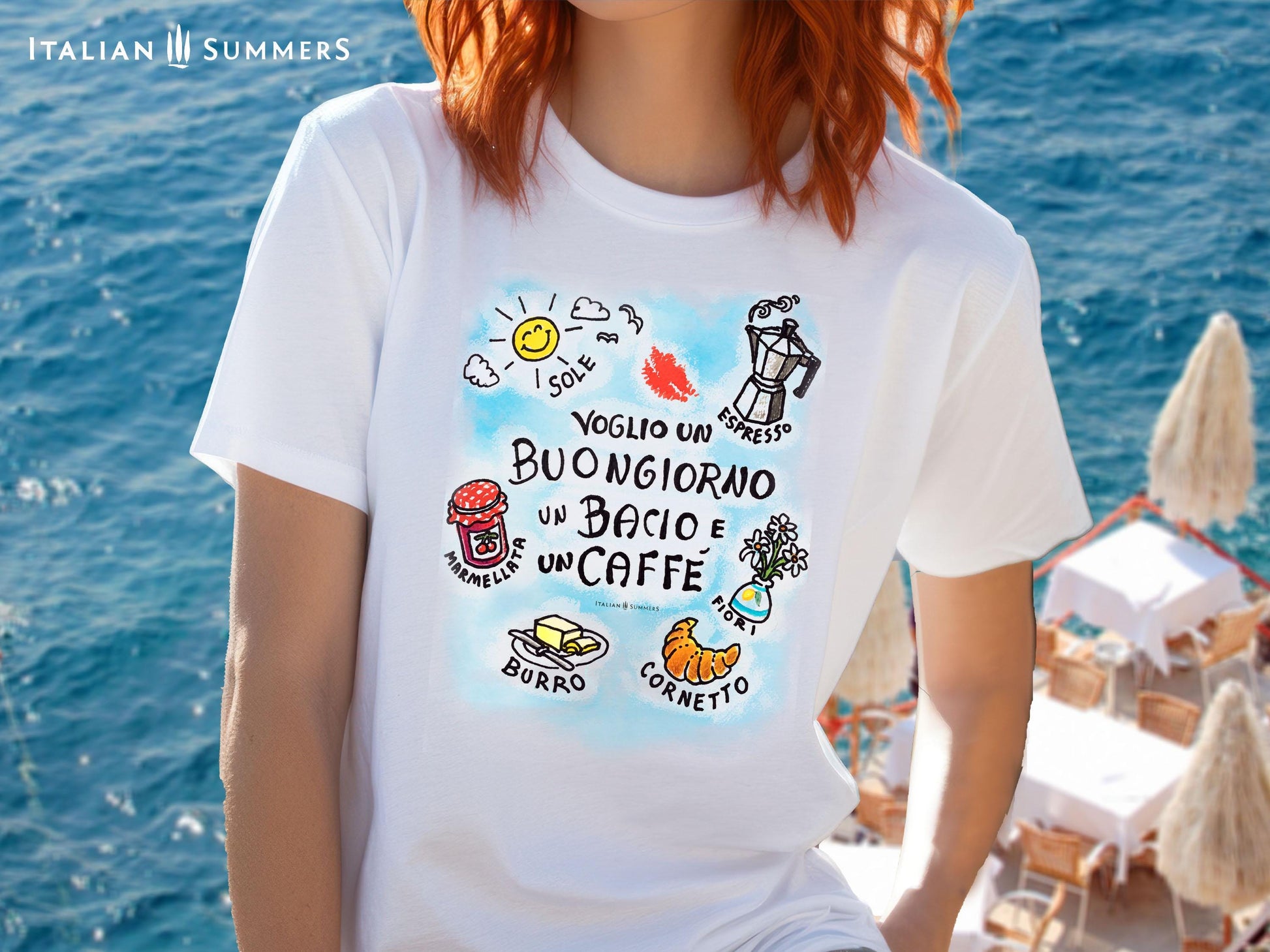 A T-shirt featuring the handwritten Italian phrase Voglio un Buongiorno, un bacio e un caffè, surrounded by sketches of an espresso machine, marmellata, a cornetto, burro, a vase of flowers, and the sun perfect for Italian coffee lovers and fans of la dolce vita. By Italian Summers.