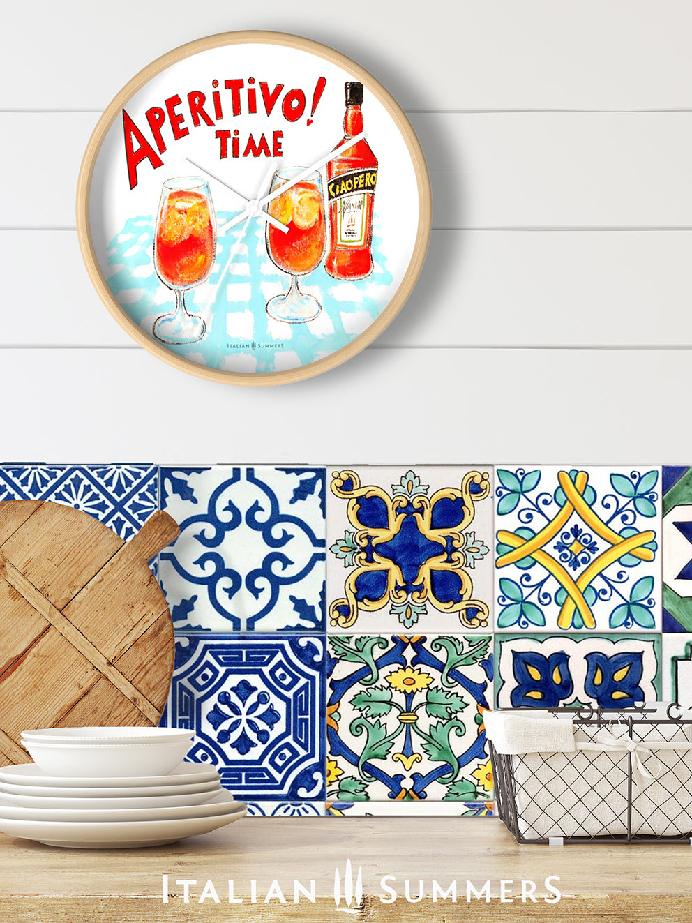 An Italy inspired rond clock with a print of Two glasses and a bottle of Aperol, whizh is called in the sketch Ciaoperol. The bottle and the foot glasses are standing on a light blue checkered table cloth. There is on top of the sketch the text 'Aperitivo time!' in a vintage red color, handwritten font. Made by Italian Summers