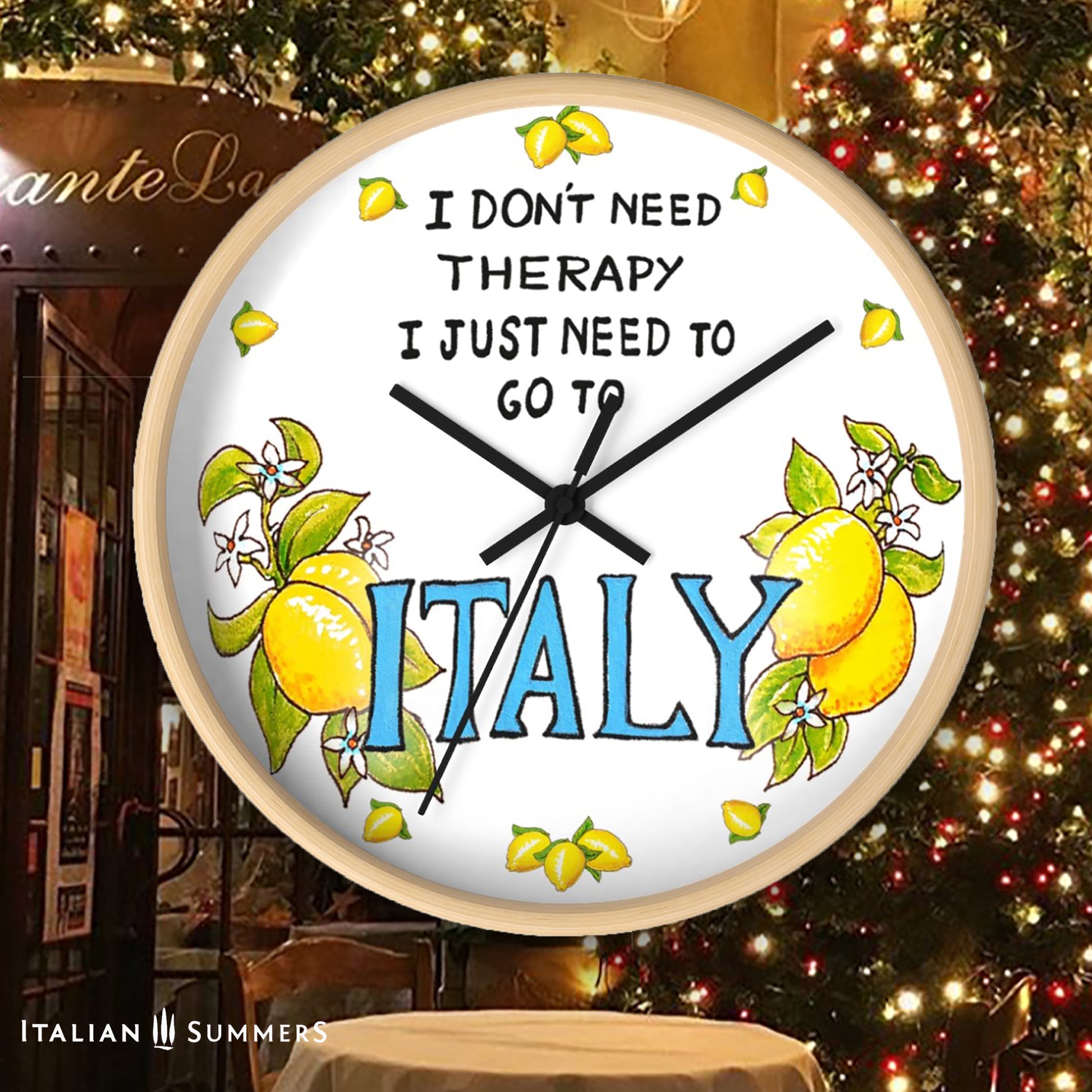 Italy inspired wall clock with the quote "I don't need therapy, I just need to go to Italy" . The quote is in the top center of the clock in balck handriting. In the lower part of the clock there is Italy written in big blue letter with on both sides a bundle of lemons with flowers. In stead of numbers there are little lemons. The body if the clock is available in wood color and white. The hands color is available in white and black. Made by Italian Summers.