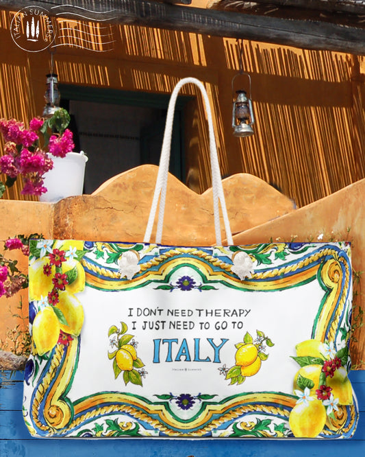 Large Italy inspired beach bag with the quote I don't need therapy, I just need to go to Italy. The Italy is in blue and on both sides of Italy are Sorrento lemons. The rims of the bag are decorated with Sicilian baroque convolutes, lemons and pieces of tiles. Printed on 2 sides. The bag has soft rope handles.
