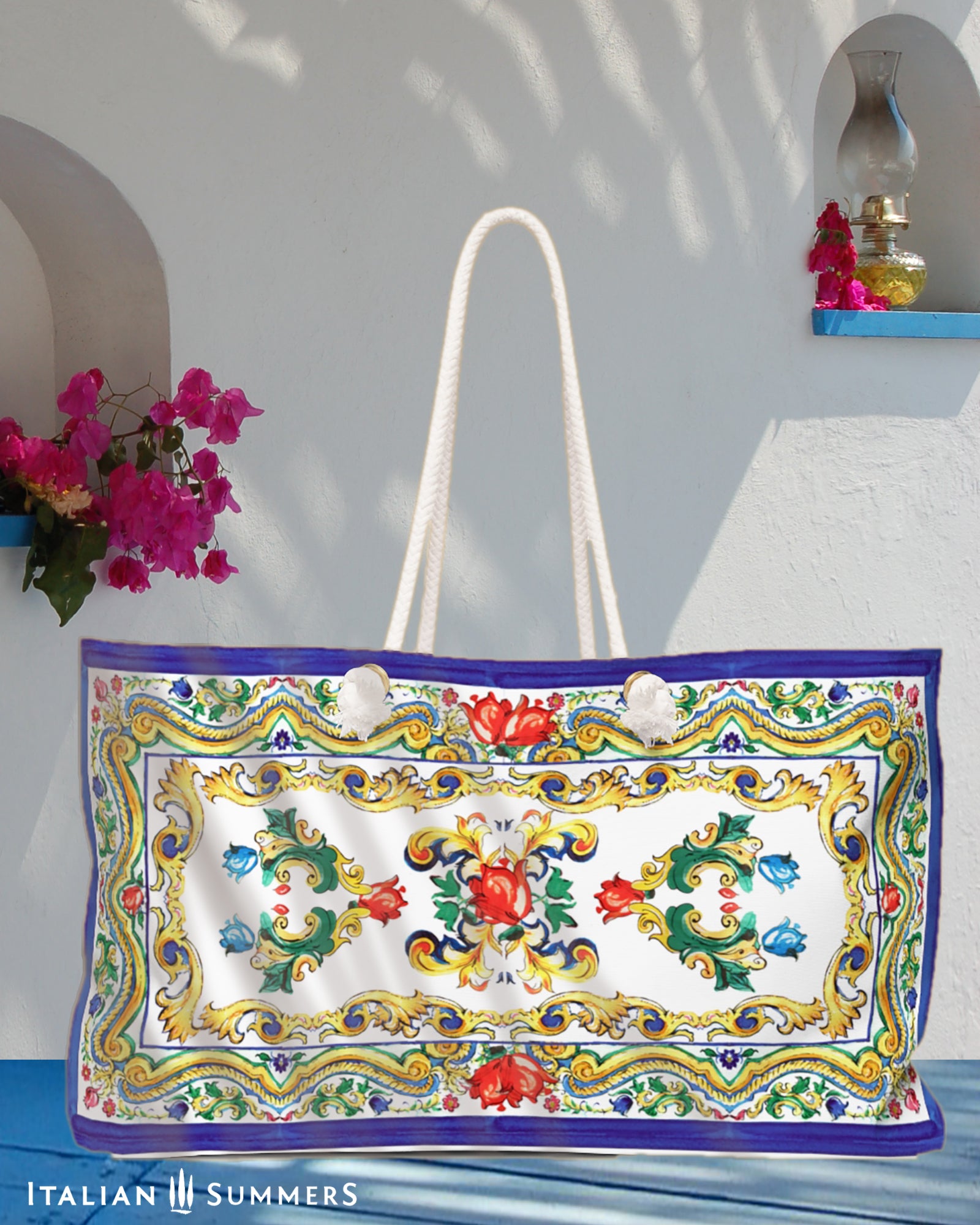 Italy beach bag inspired Sicilian baroque convolutes, Sicilian tiles and flowers. on the tim and bottom of the bag is a blue border. Main colors of the flowes/tiles are blue, red and green. The beach bag has soft rope handles. Designed by Italian Summers.