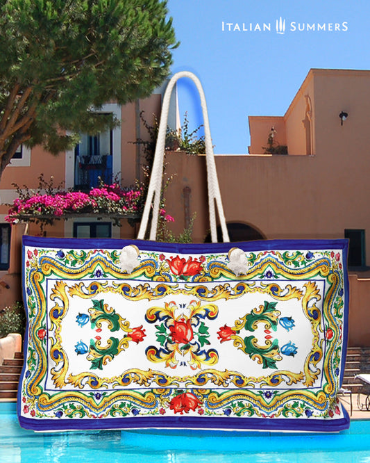 Italy beach bag inspired Sicilian baroque convolutes, Sicilian tiles and flowers. on the tim and bottom of the bag is a blue border. Main colors of the flowes/tiles are blue, red and green. The beach bag has soft rope handles. Designed by Italian Summers.