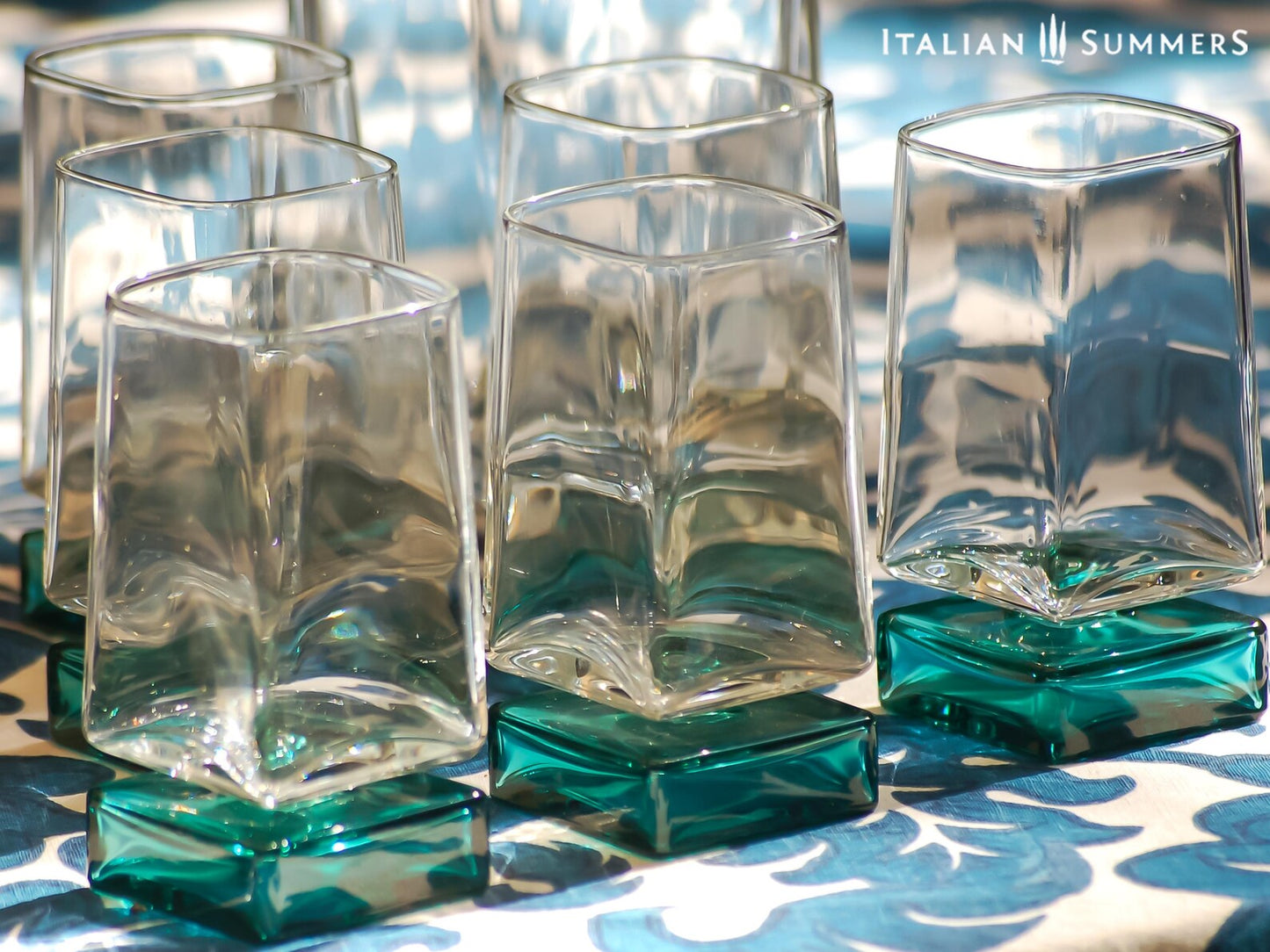 Vintage Bormioli Monet glass set from Italy, featuring square whiskey glasses with bold green foot and matching decanter, displayed on a table in retro style.