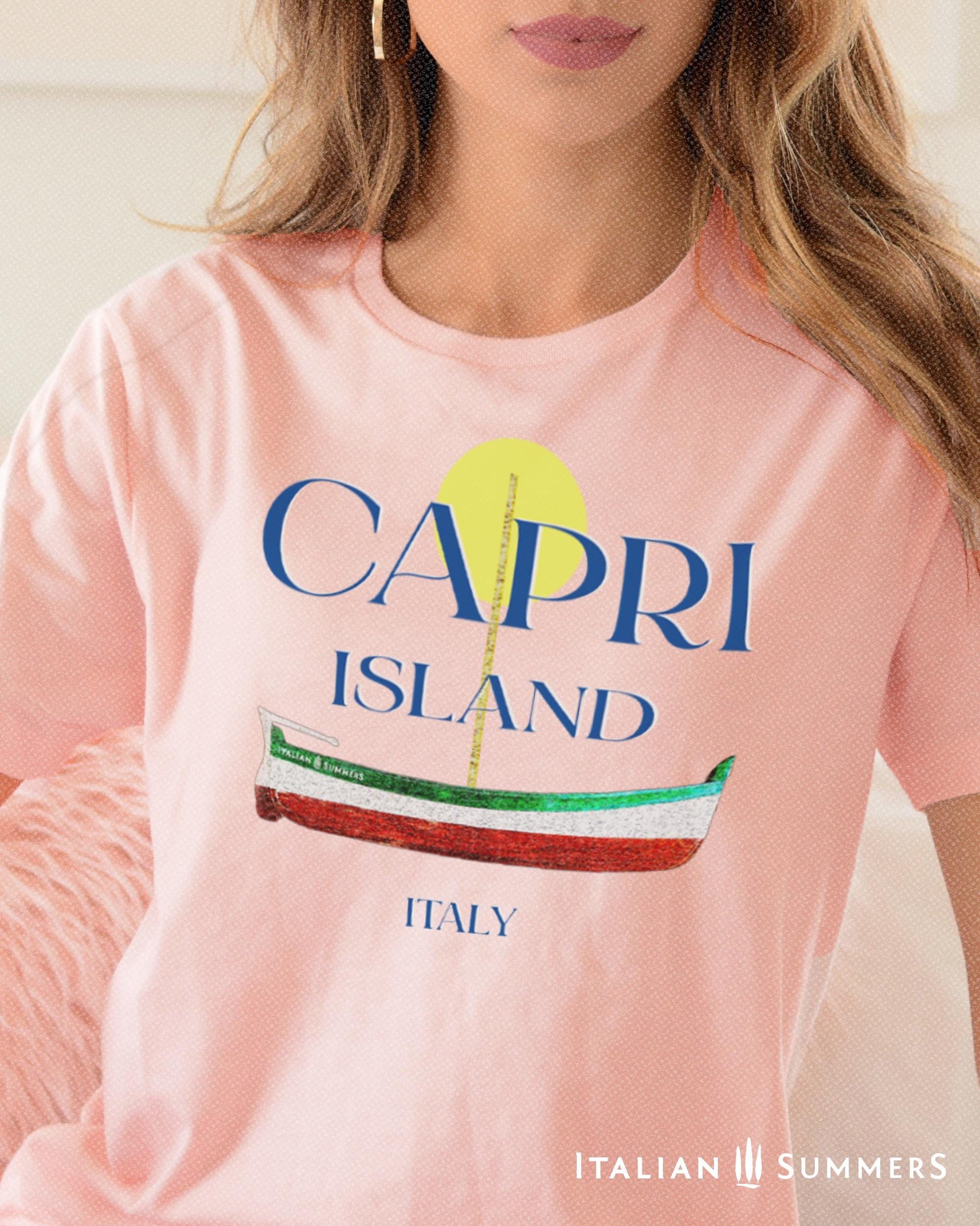 A Garment-dyed quality pink T shirt with a print of a traditional Capri Island wooden boat in the color of the Italian flag, and the text CAPRI in capital letters above it, with a full-moon disk above.