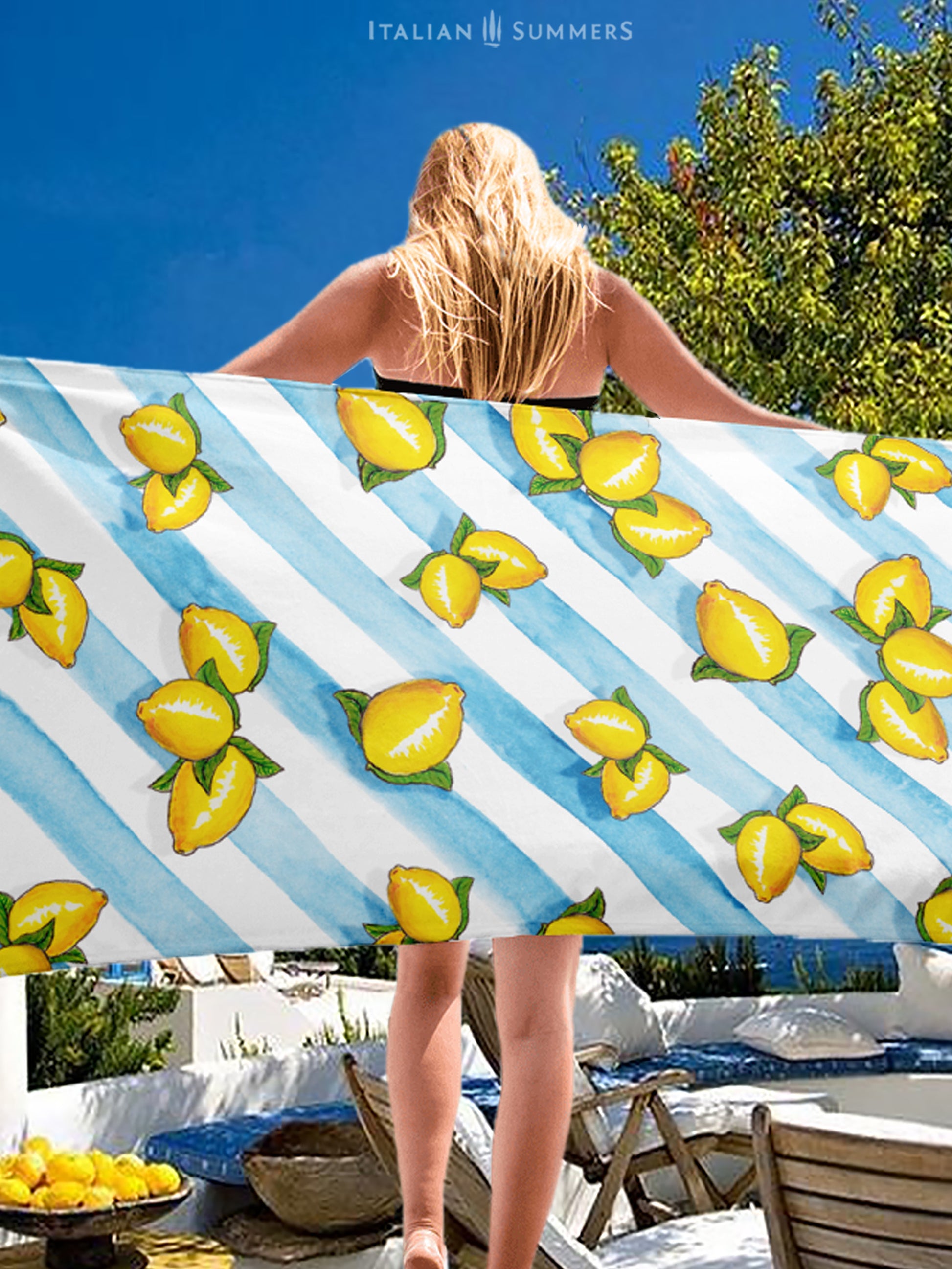 A large beach towel with printed Sorrento lemons on a background of aqua blue water color stripes. A happy and sunny Italian summer feeling. Made by Italian Summers