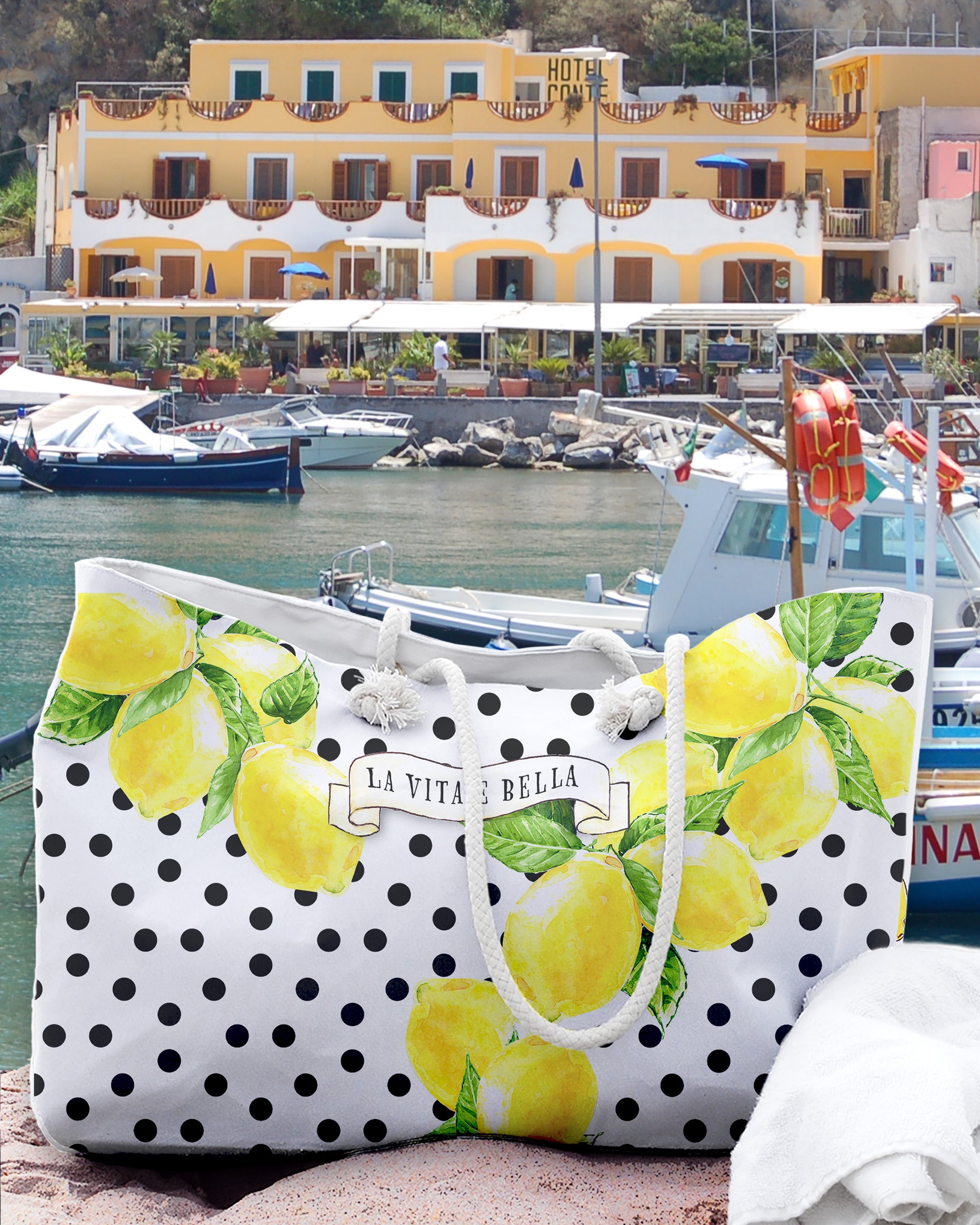 Italy inspired large beach bag with a white background and black polka dots. Big Sorrento lemons on two sides and the writing La vita 'e bella on a scroll in the middle of the bage. Designed by Italian Summers