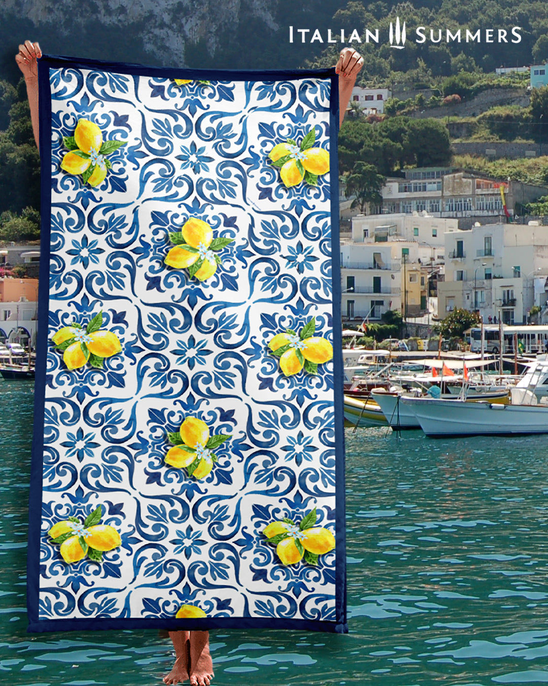 A beautiful Italy inspired beach towel printed with a pattern of blue Italian Maiolica tiles, a deep blue framing stripe and happy bunches of Sorrento lemons with flowers. Made by Italian Summers