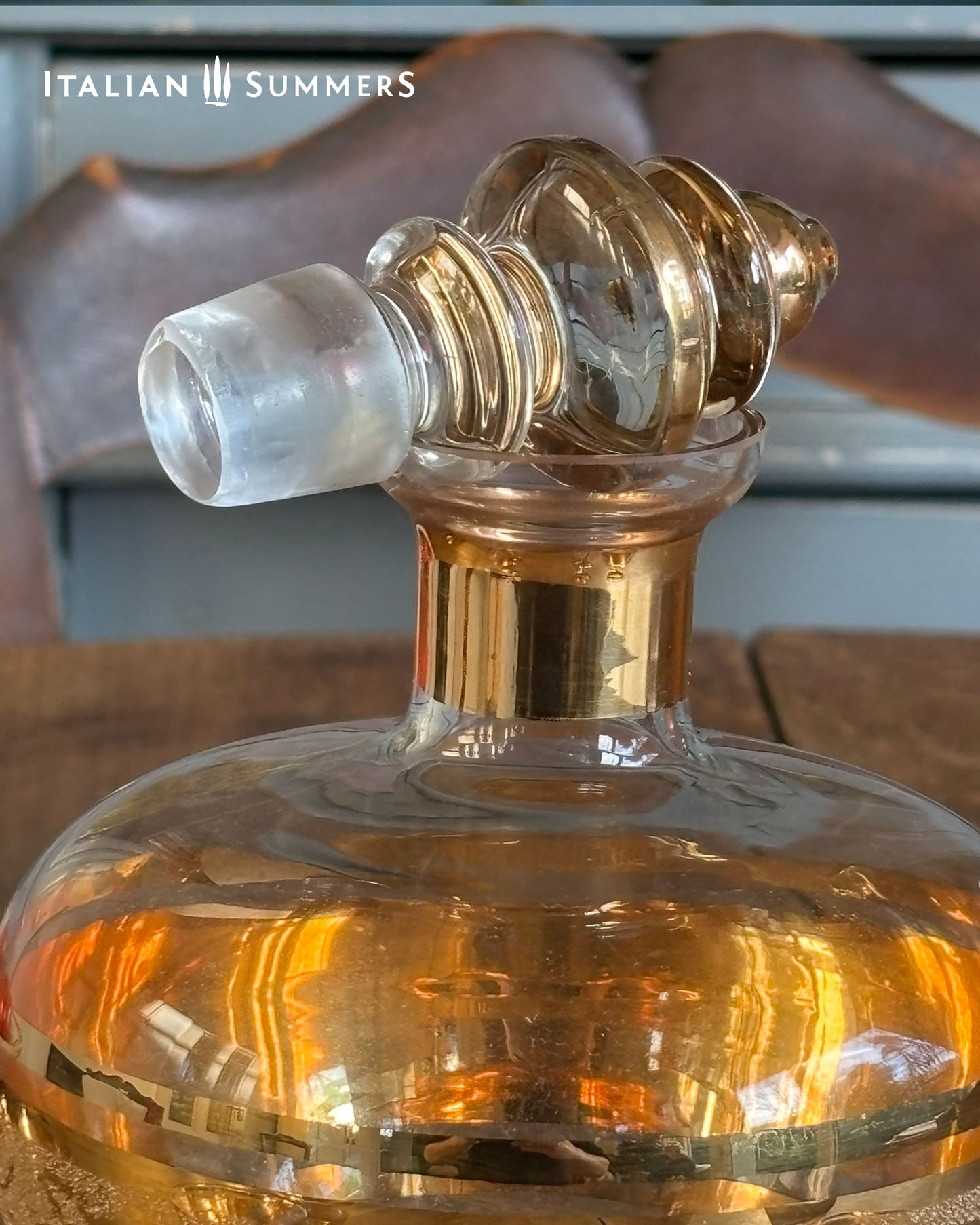 Decorative glass bottle with gold bands and elegant gold stopper, brand 'Italian Summers' visible