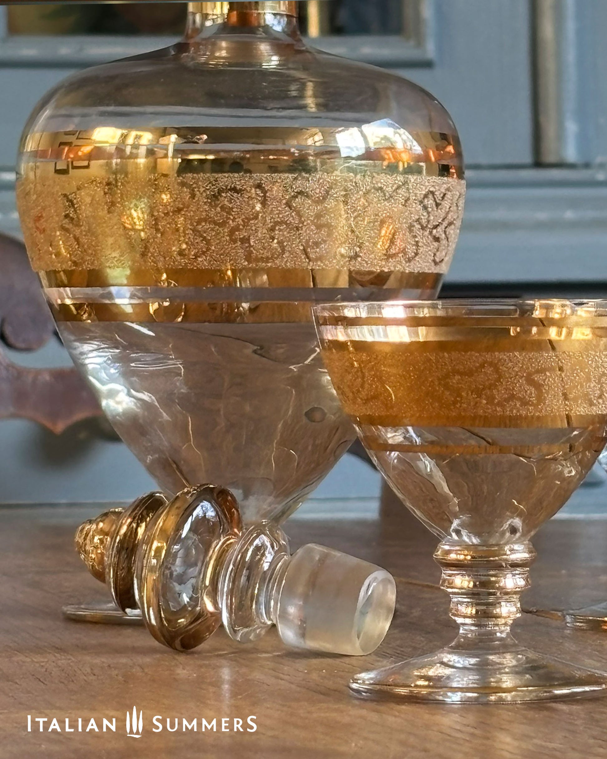 Decorative glass bottles with gold accents on a wooden surface, featuring the brand 'Italian Summers'.