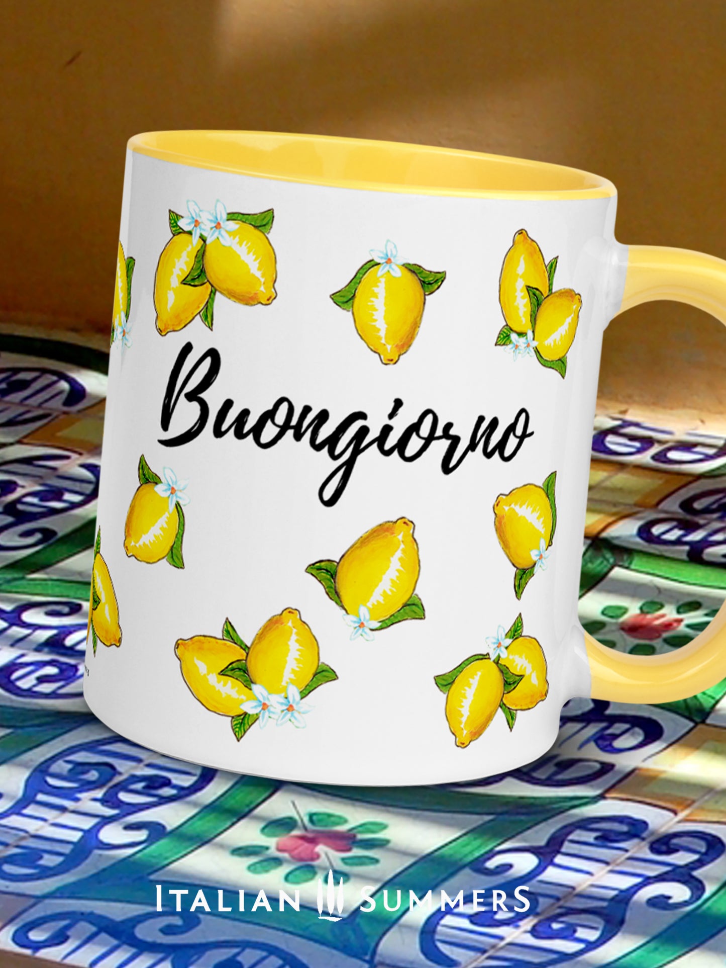 Italy inspired coffee mug with happy sketched lemons over the whole mug on all sidesand a playful Buongiorno writing beteen the lemons. The inside and handle of the mug are yellow. On the lemons are little lemon flowers. Made by Italian Summers